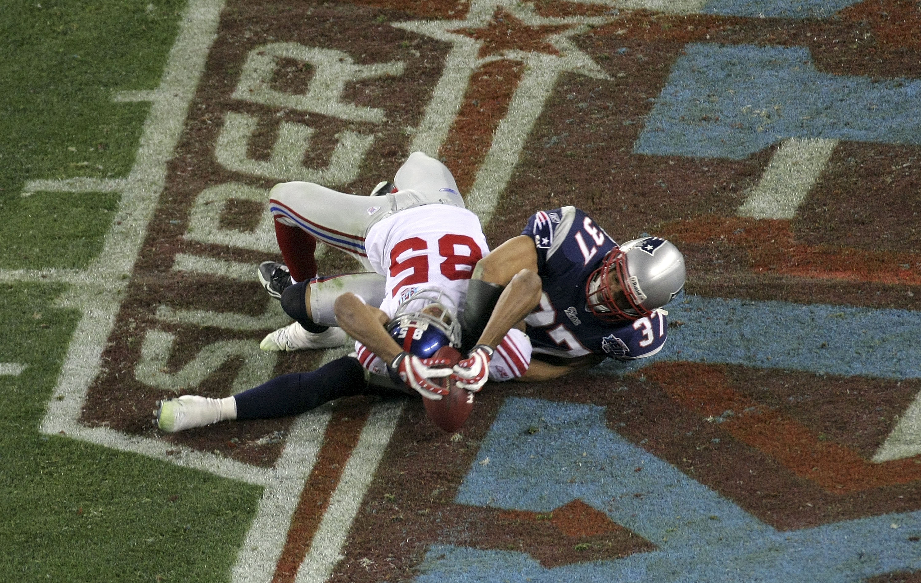 GLENDALE, AZ - FEBRUARY 03:  David Tyree #85 of the New York Giants catches a 32-yard pass from Eli Manning #10 as Rodney Harrison #37 of the New England Patriots attempts to knock it out in the fourth quarter of Super Bowl XLII on February 3, 2008 at the