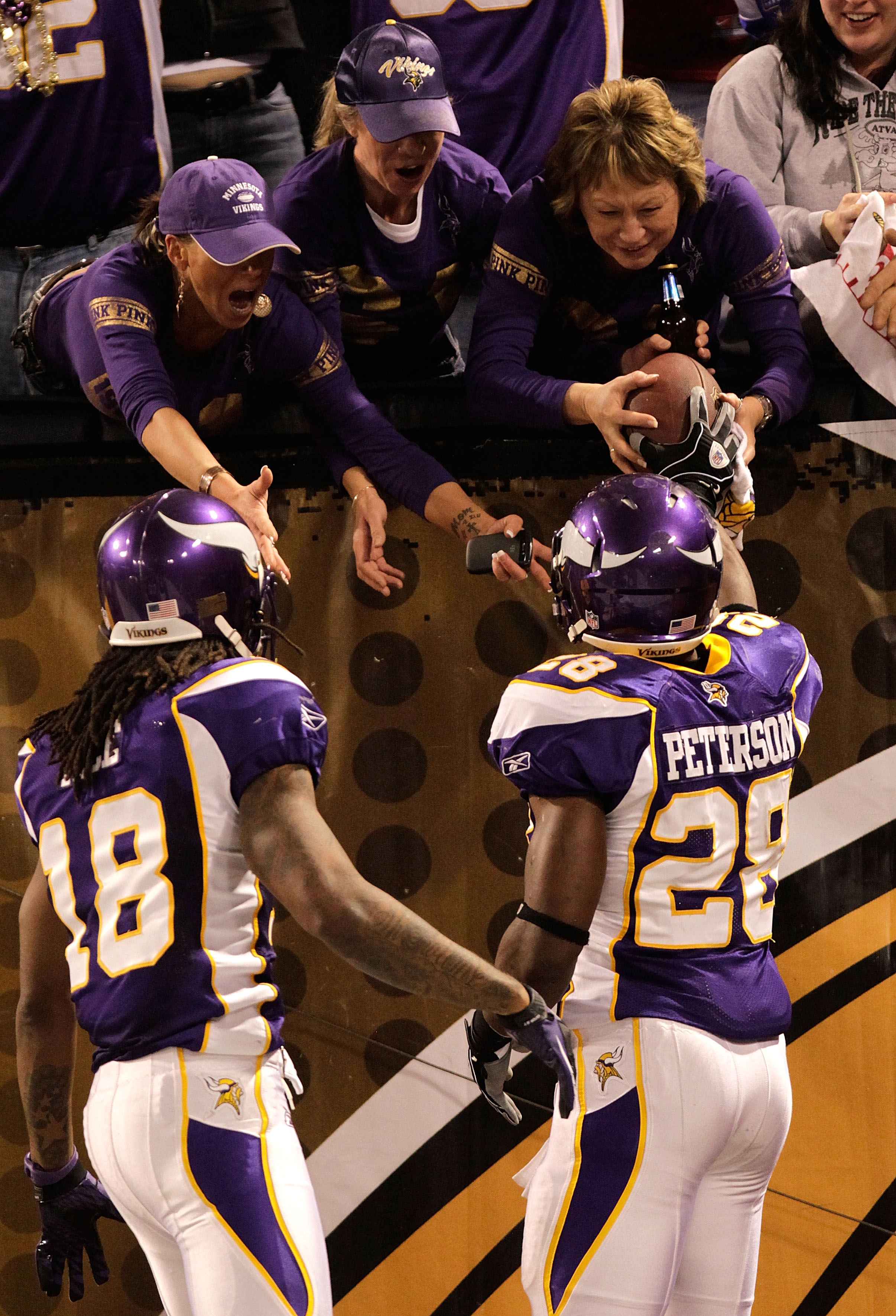 MINNEAPOLIS, MN - DECEMBER 05:  Adrian Peterson #28 of the Minnesota Vikings hands the ball to a fan alongside teammate Sidney Rice #18 after he rushed for a touchdown against the Buffalo Bills at the Mall of America Field at the Hubert H. Humphrey Metrod