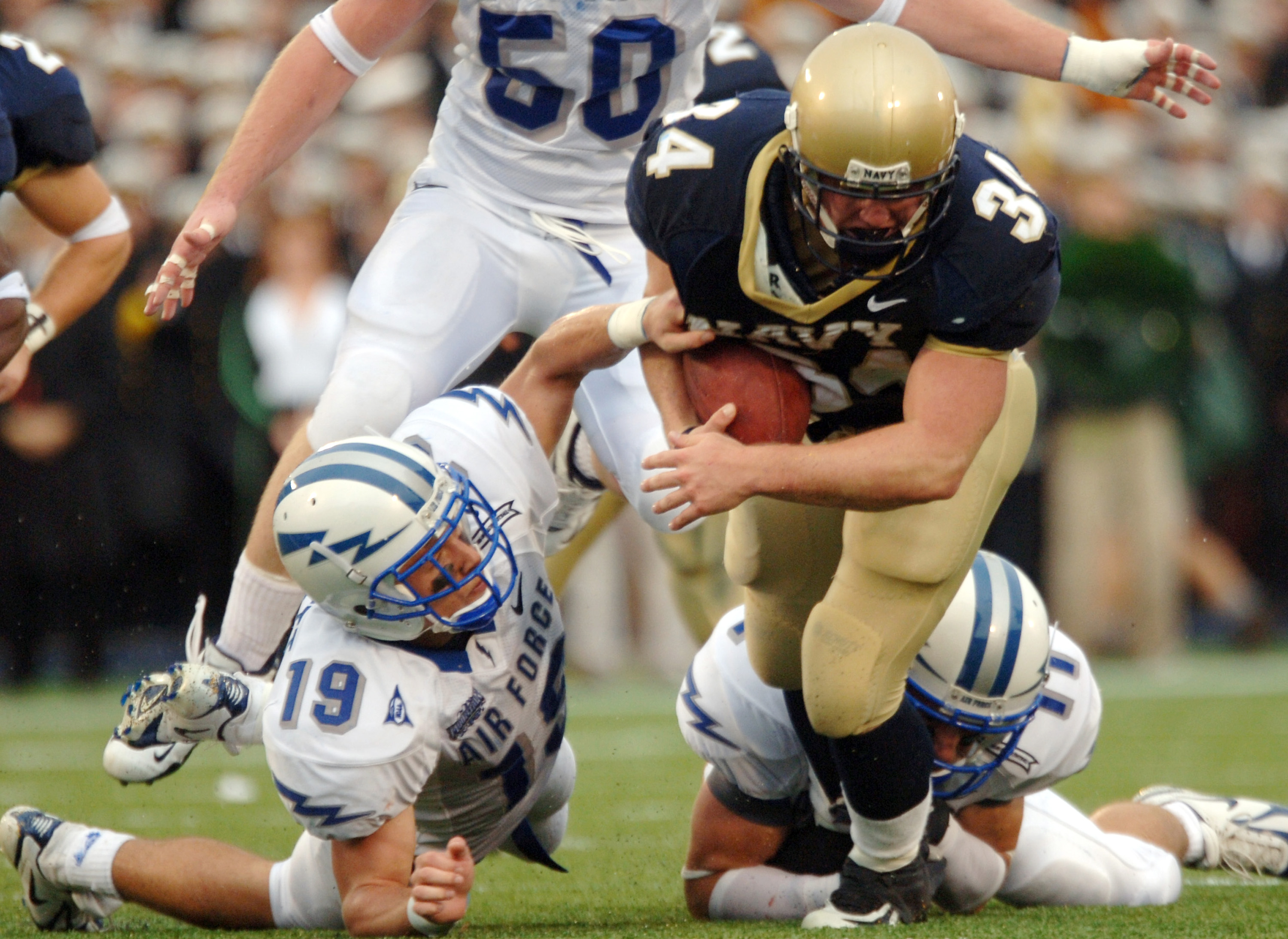 ANNAPOLIS, MD - OCTOBER 8: In this handout provieded by the U.S. Navy, U.S. Naval Academy Midshipman full back Matt Hall is pulled down by Air Force free safety Ty Paffett #19 and free safety Bobby Giannini #11 during the 2nd quarter of play on October 8