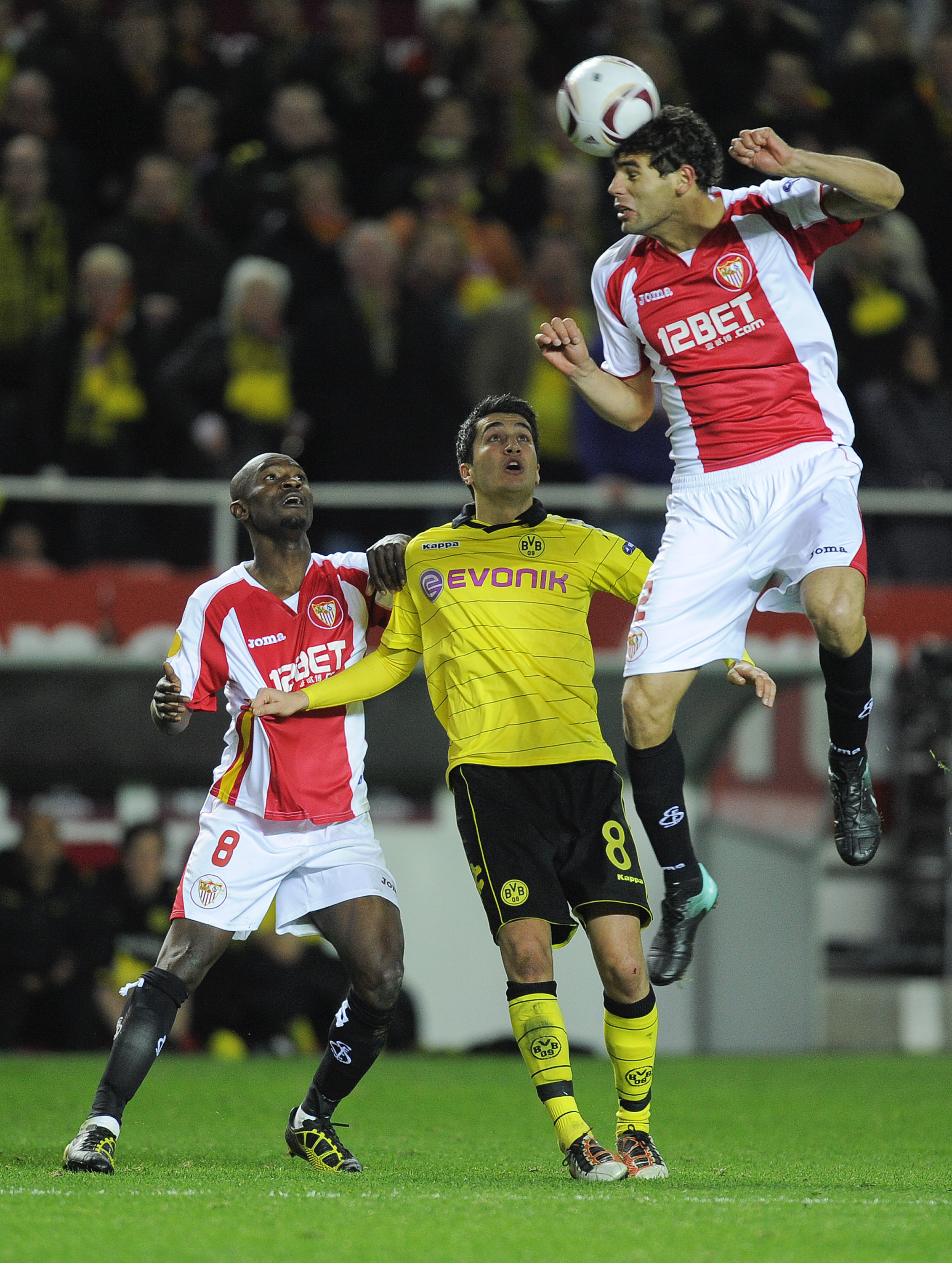 SEVILLE, SPAIN - DECEMBER 15: Nuri Sahin of Borussia Dortmund (C), Didier Zokora of Sevilla FC (L) and Federico Fazio of Sevilla FC duel for a high ball during the UEFA Europa League group J match between Sevilla and Borussia Dortmund at Estadio Ramon San