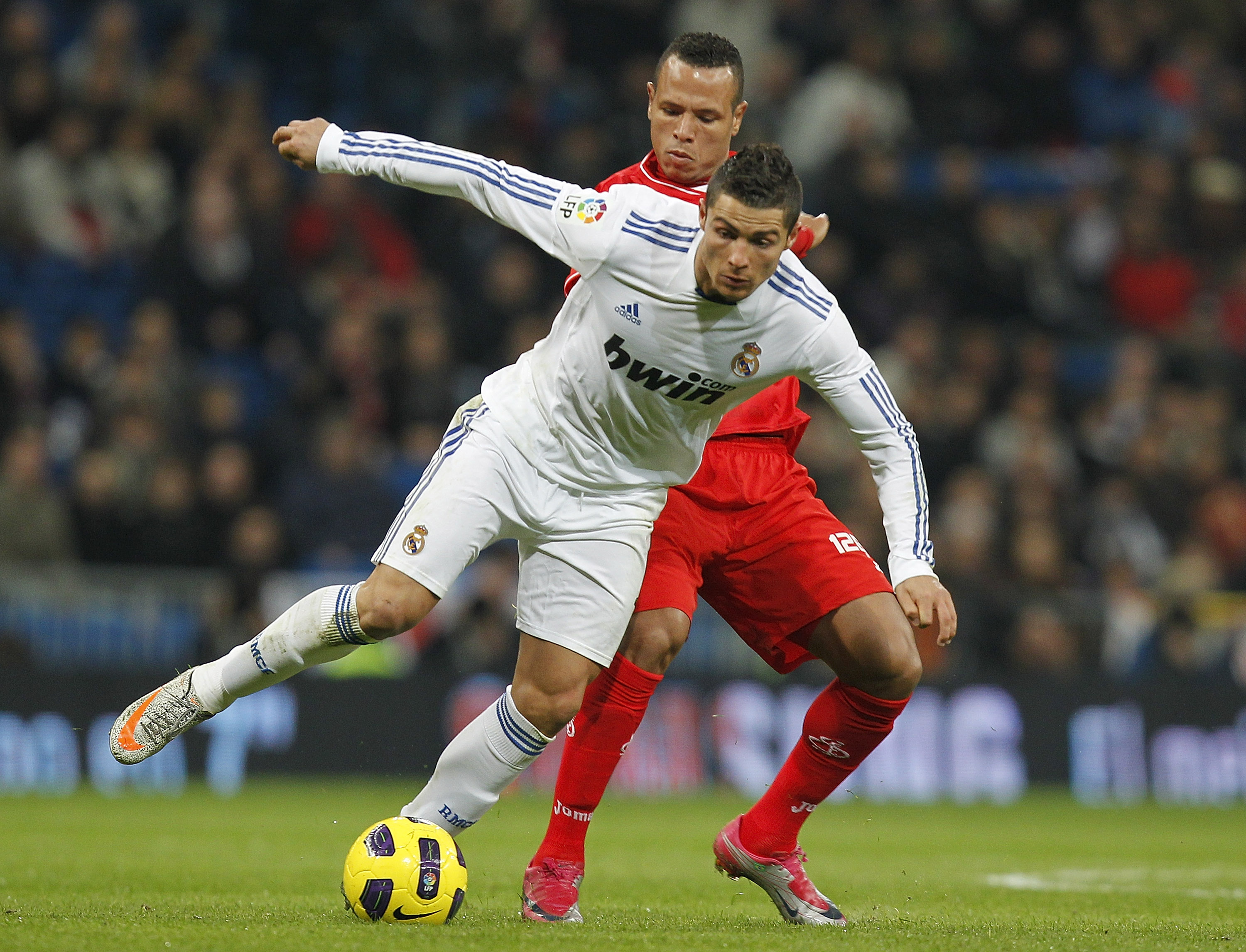 MADRID, SPAIN - DECEMBER 19:  Cristiano Ronaldo of Real Madrid fights for the ball with Luis Fabiano of Sevilla during the La Liga match between Real Madrid and Sevilla at Estadio Santiago Bernabeu on December 19, 2010 in Madrid, Spain. Real Madrid won th