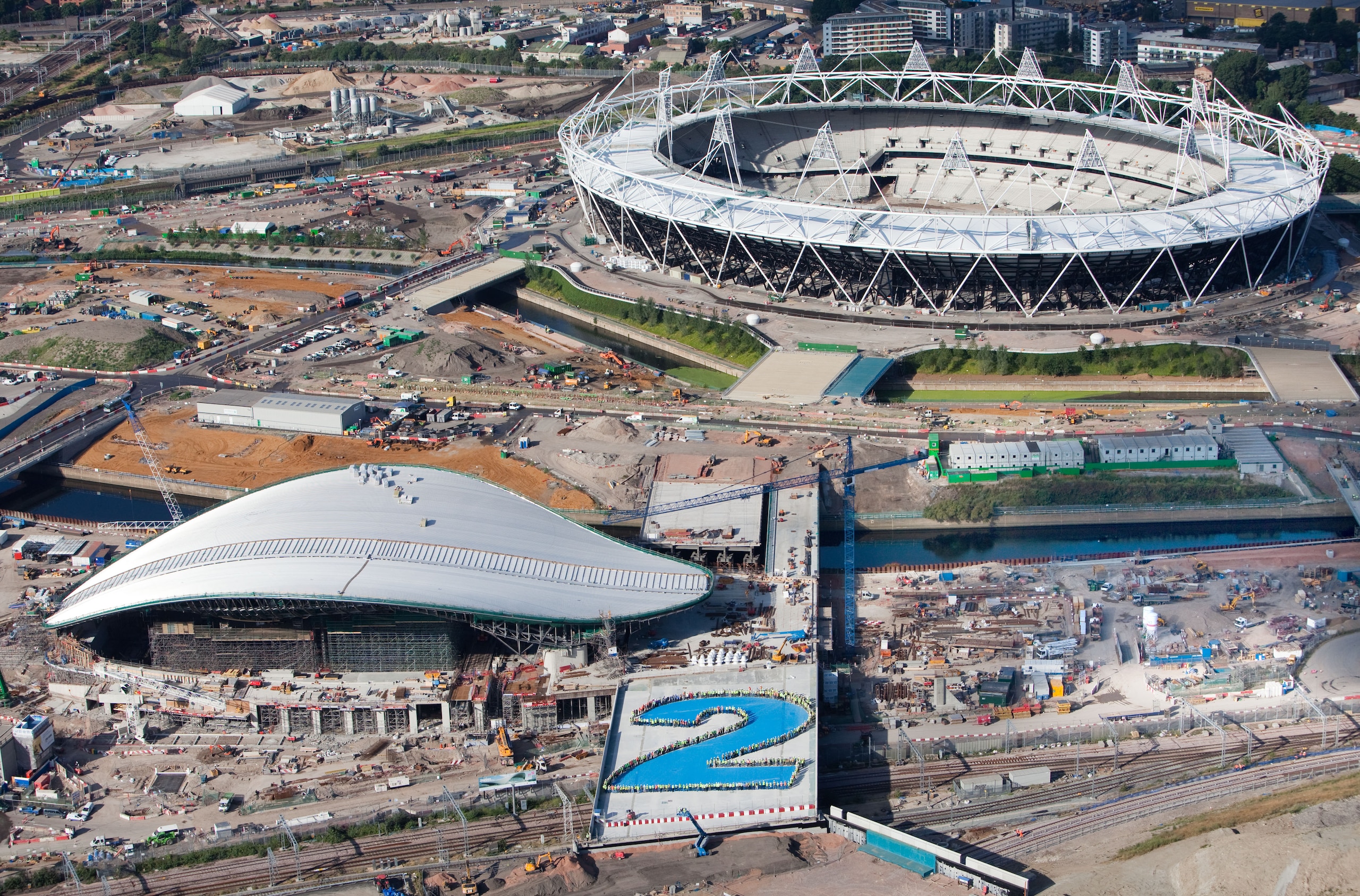 LONDON - JULY 21: In this handout image provided by London 2012, an aerial view of the F10 bridge with construction workers from the Aquatics Centre forming a giant number 2 to signify 2 years until the start of London 2012 Olympic Games on July 21, 201 LONDON - JULY 21: In this handout image provided by London 2012, an aerial view of the F10 bridge with construction workers from the Aquatics Centre forming a giant number 2 to signify 2 years until the start of London 2012 Olympic Games on July 21, 201