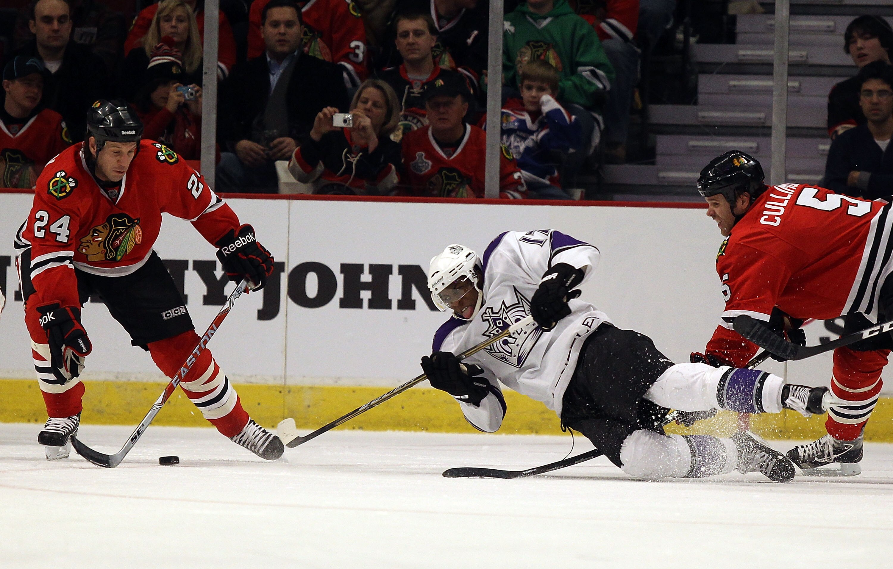 CHICAGO, IL - DECEMBER 19: Wayne Simmonds #17 of the Los Angeles Kings falls to the ice while trying to pass between Nick Boynton #24 and Jassen Cullimore #5 of the Chicago Blackhawks at the United Center on December 19, 2010 in Chicago, Illinois. The Bla