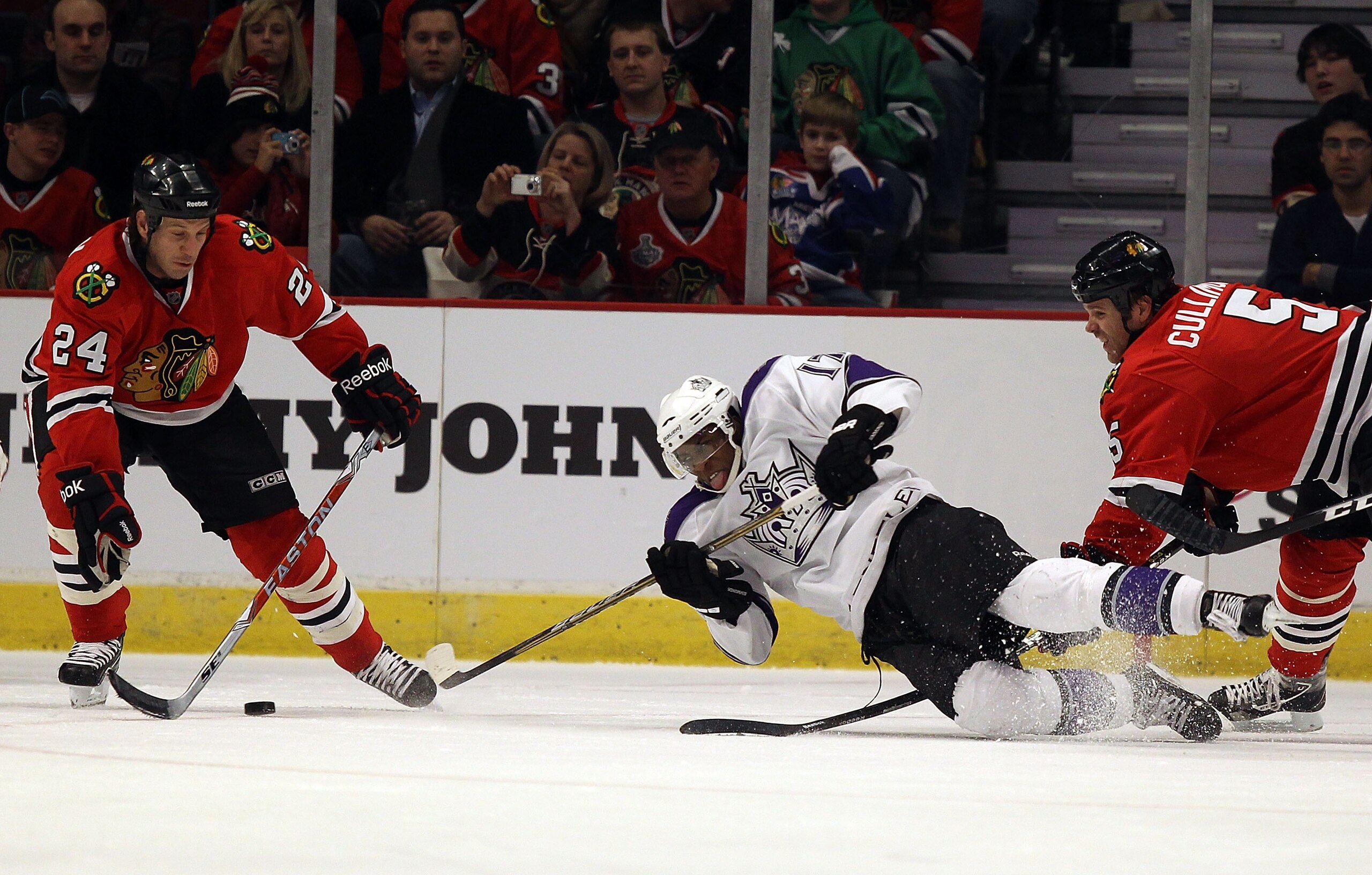 CHICAGO, IL - DECEMBER 19: Wayne Simmonds #17 of the Los Angeles Kings falls to the ice while trying to pass between Nick Boynton #24 and Jassen Cullimore #5 of the Chicago Blackhawks at the United Center on December 19, 2010 in Chicago, Illinois. The Bla