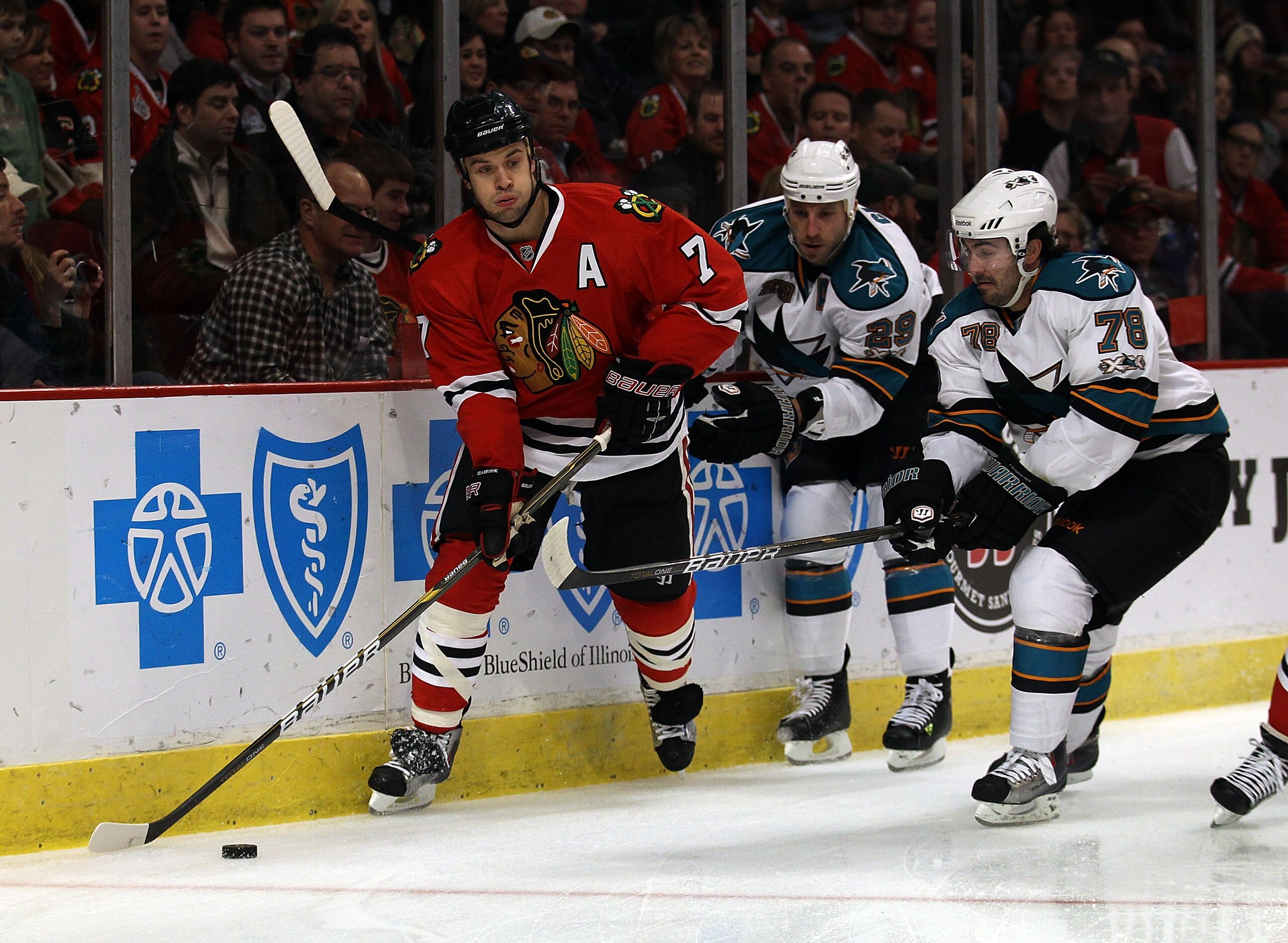 CHICAGO, IL - DECEMBER 30: Brent Seabrook #7 of the Chicago Blackhawks looks to pass under pressure from Ryane Clowe #29 and Benn Ferriero #78 of the San Jose Sharks at the United Center on December 30, 2010 in Chicago, Illinois. (Photo by Jonathan Daniel