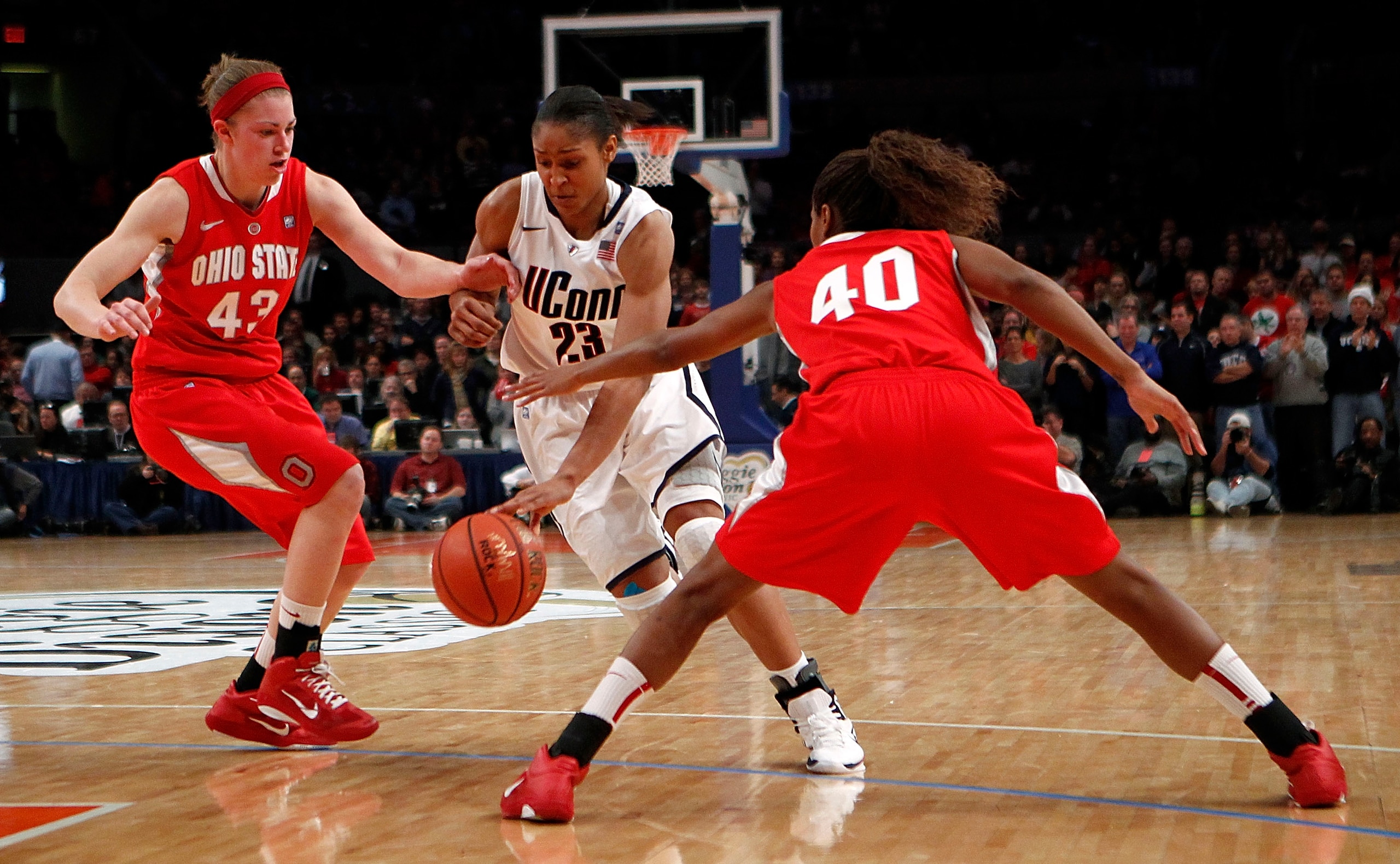 NEW YORK - DECEMBER 19:  Maya Moore #23 of the Connecticut Huskies drives between Sarah Schulze #43 and Brittany Johnson #40 of the Ohio State Buckeyes in the Maggie Dixon Classic at Madison Square Garden on December 19, 2010 in New York City.  (Photo by