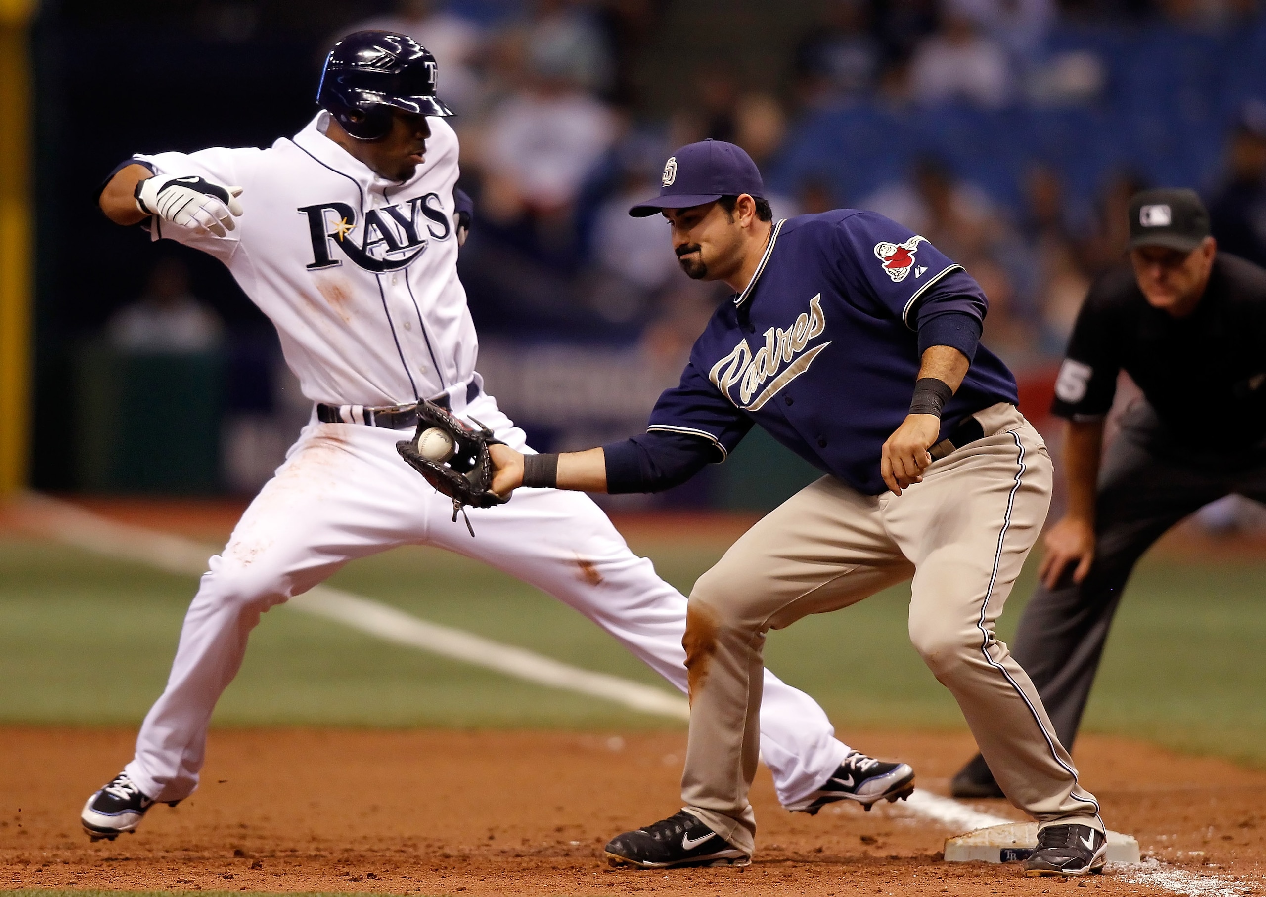ST. PETERSBURG - JUNE 22:  Outfielder Carl Crawford #13 of the Tampa Bay Rays gets back to first safely as first baseman Adrian Gonzalez #23 of the San Diego Padres takes the throw during the game at Tropicana Field on June 22, 2010 in St. Petersburg, Flo