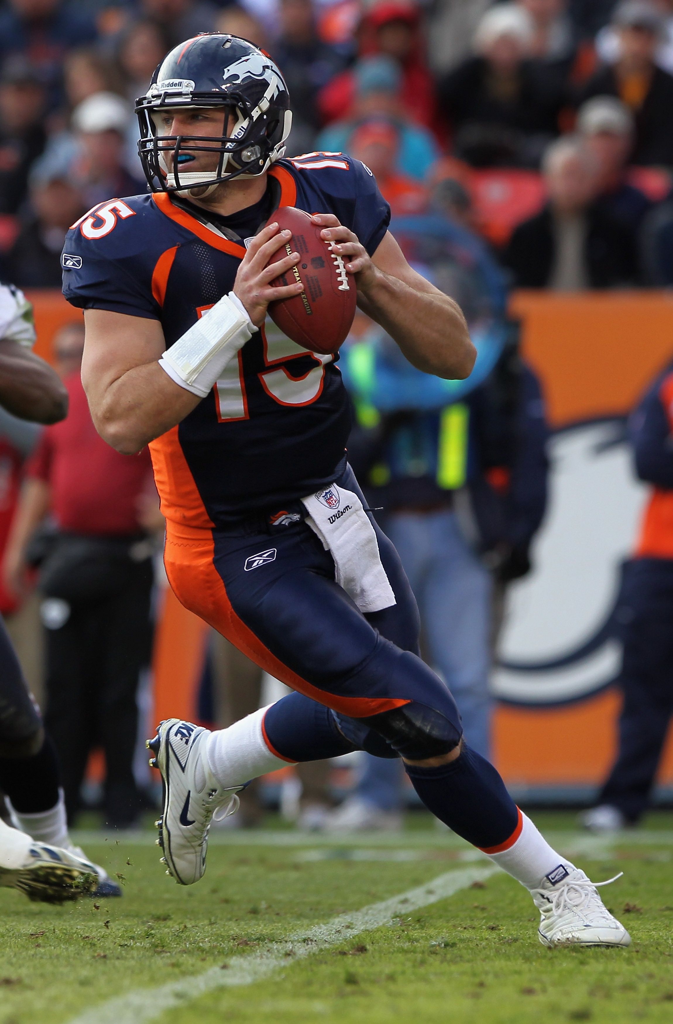 DENVER - DECEMBER 26:  Quarterback Tim Tebow #15 of the Denver Broncos rolls out and looks to deliver a pass against the Houston Texas at INVESCO Field at Mile High on December 26, 2010 in Denver, Colorado. The Broncos defeated the Texans 24-23.  (Photo b