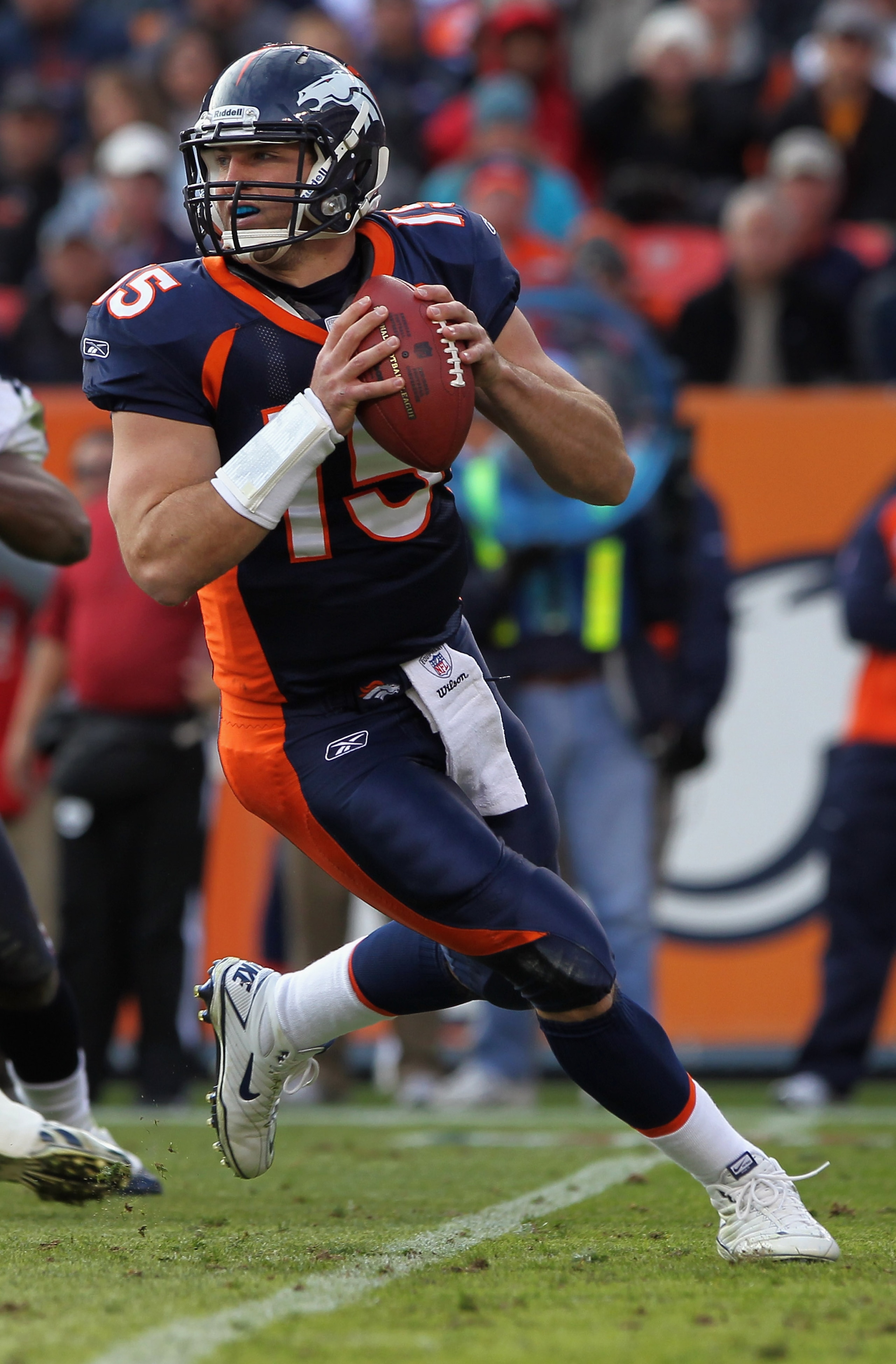 DENVER - DECEMBER 26:  Quarterback Tim Tebow #15 of the Denver Broncos rolls out and looks to deliver a pass against the Houston Texas at INVESCO Field at Mile High on December 26, 2010 in Denver, Colorado. The Broncos defeated the Texans 24-23.  (Photo b