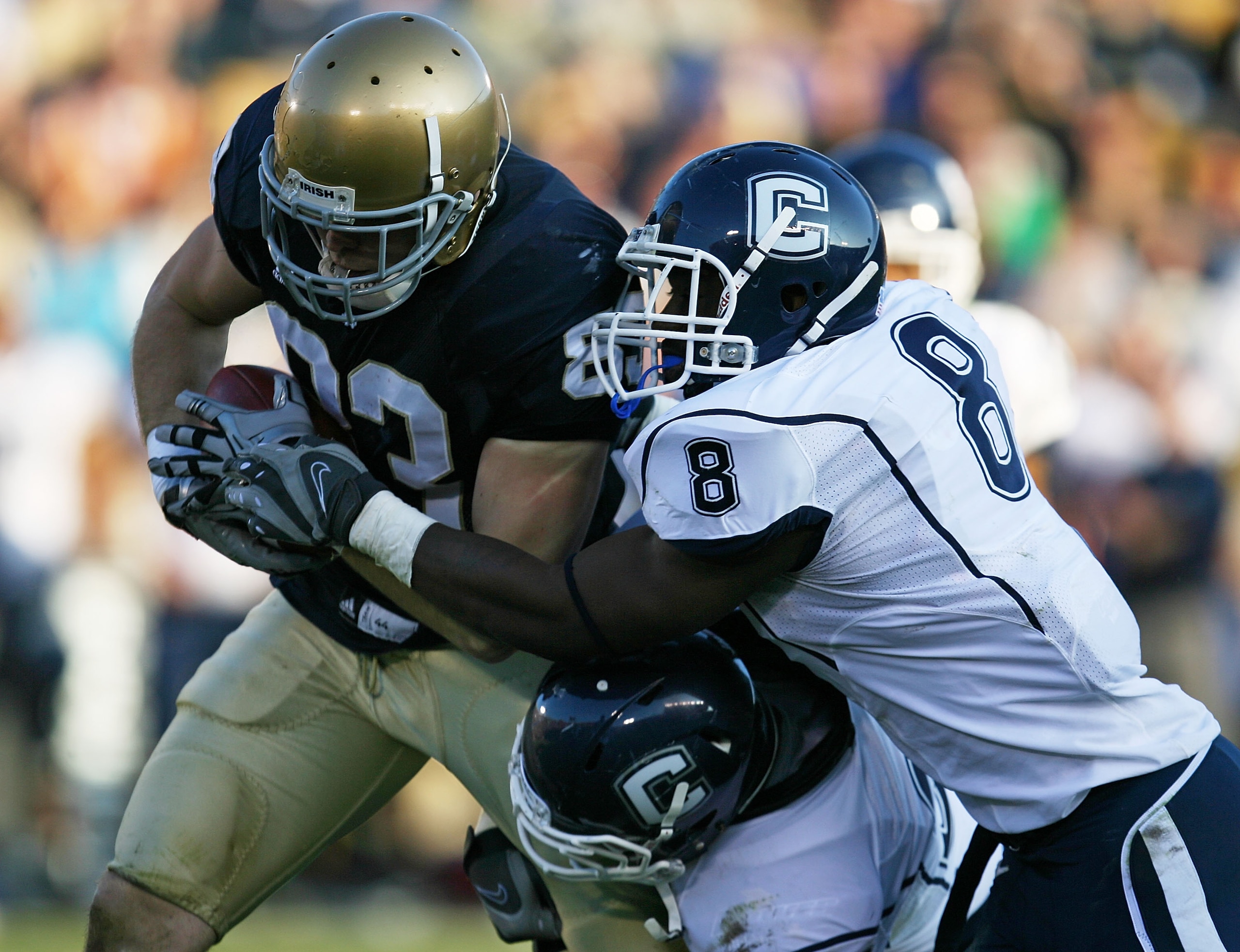 SOUTH BEND, IN - NOVEMBER 21: Robby Parris #82 of the Notre Dame Fighting Irish is brought down by Robert Vaughn #33 and Lawrence Wilson #8 of the Univeristy of Connecticut Huskies at Notre Dame Stadium on November 21, 2009 in South Bend, Indiana. Connect