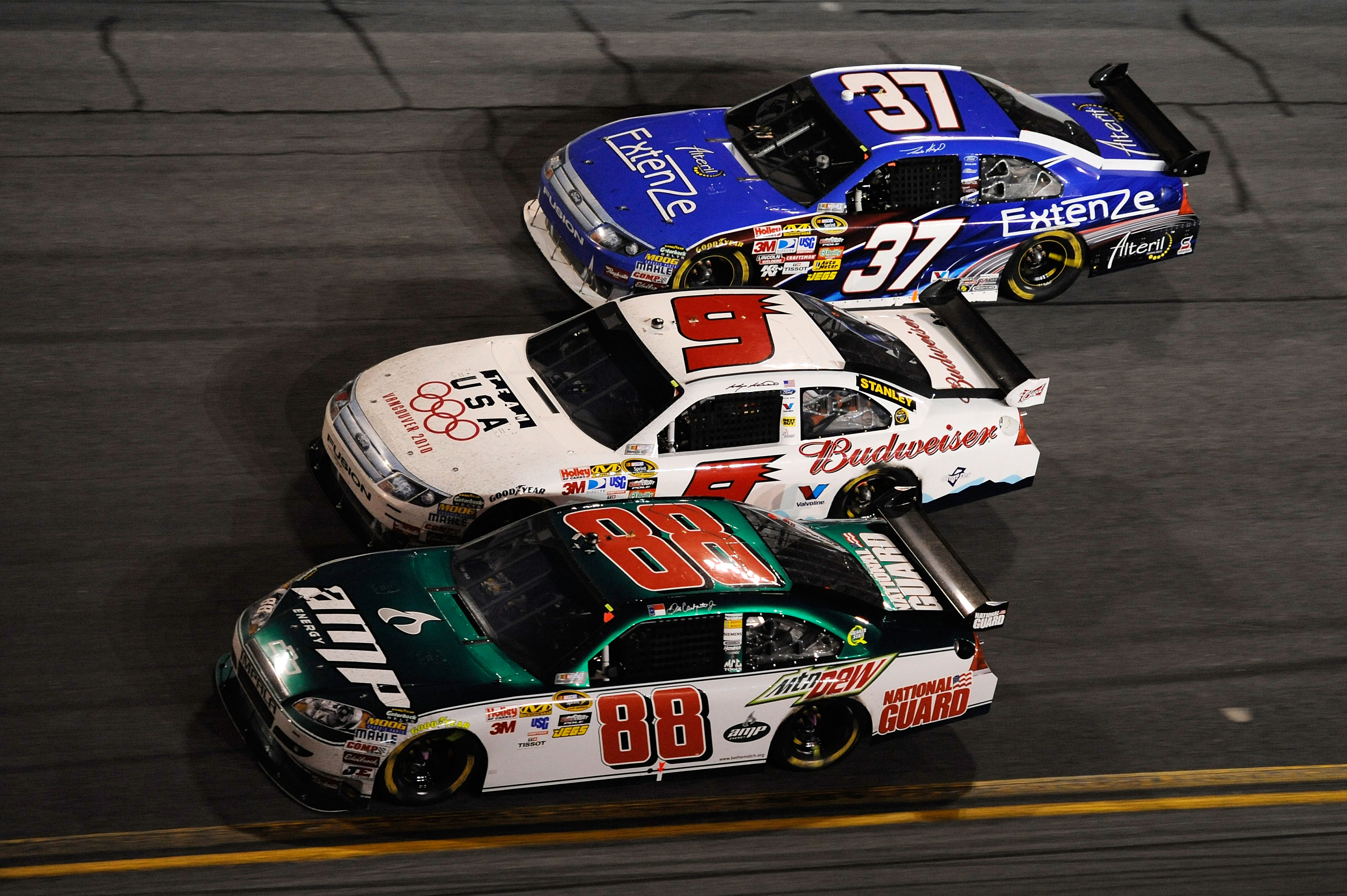 DAYTONA BEACH, FL - FEBRUARY 14:  Dale Earnhardt Jr., driver of the #88 AMP Energy/National Guard Chevrolet, races Kasey Kahne, driver of the #9 Budweiser Ford, and Travis Kvapil, driver of the #37 Extenze Ford, during the NASCAR Sprint Cup Series Daytona