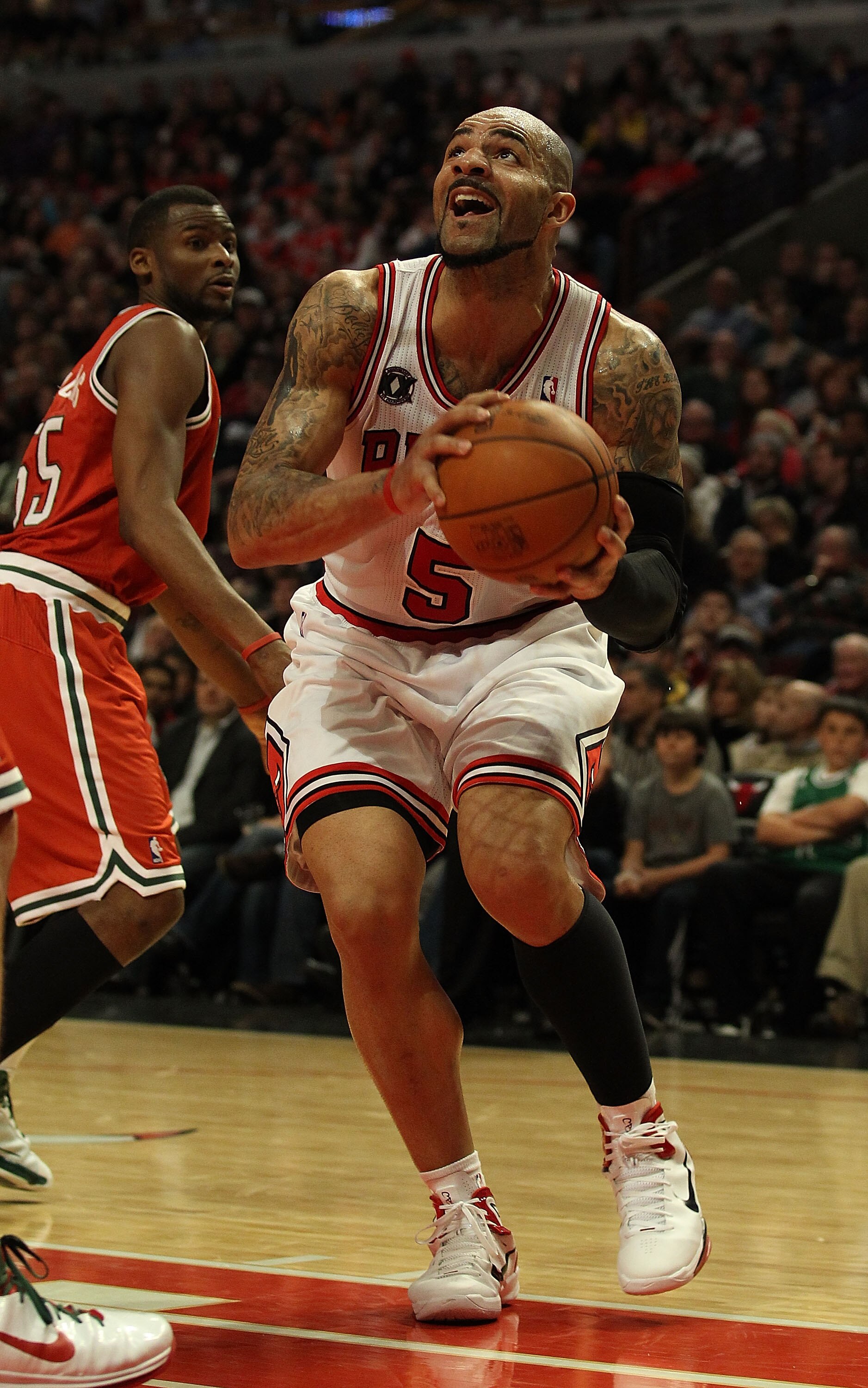 CHICAGO, IL - DECEMBER 28: Carlos Boozer #5 of the Chicago Bulls goes up for a shot past Keyon Dooling #55 of the Milwaukee Bucks at the United Center on December 28, 2010 in Chicago, Illinois. The Bulls defeated the Bucks 90-77. NOTE TO USER: User expres CHICAGO, IL - DECEMBER 28: Carlos Boozer #5 of the Chicago Bulls goes up for a shot past Keyon Dooling #55 of the Milwaukee Bucks at the United Center on December 28, 2010 in Chicago, Illinois. The Bulls defeated the Bucks 90-77. NOTE TO USER: User expres