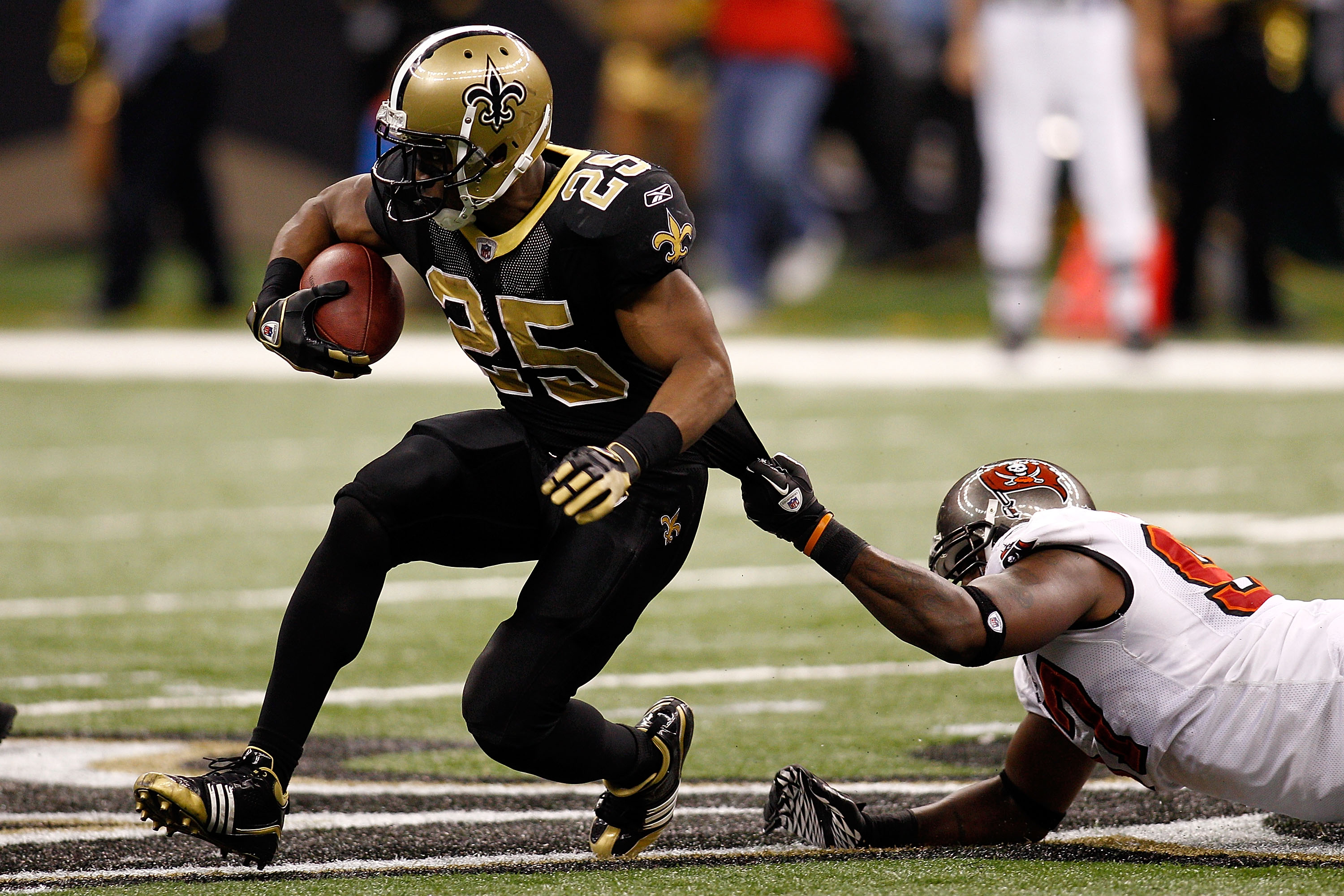 NEW ORLEANS, LA - JANUARY 02:  Reggie Bush #25  of the New Orleans Saints is tackled by Alex Magee #97 of the Tampa Bay Buccaneers at the Louisiana Superdome on January 2, 2011 in New Orleans, Louisiana.   The Buccaneers defeated the Saints 23-13.  (Photo
