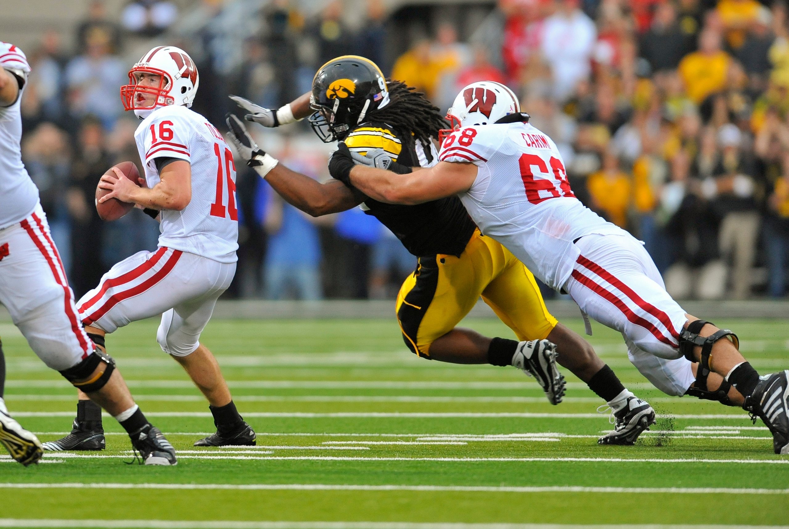 IOWA CITY, IA - OCTOBER 23- Quarterback Scott Tolzien #16 of the Wisconsin Badgers throws under pressure from Defensive lineman Adrian Clayborn #94 of the University of Iowa Hawkeyes as offensive lineman Gabe Carimi #68 defends during the first half of pl IOWA CITY, IA - OCTOBER 23- Quarterback Scott Tolzien #16 of the Wisconsin Badgers throws under pressure from Defensive lineman Adrian Clayborn #94 of the University of Iowa Hawkeyes as offensive lineman Gabe Carimi #68 defends during the first half of pl