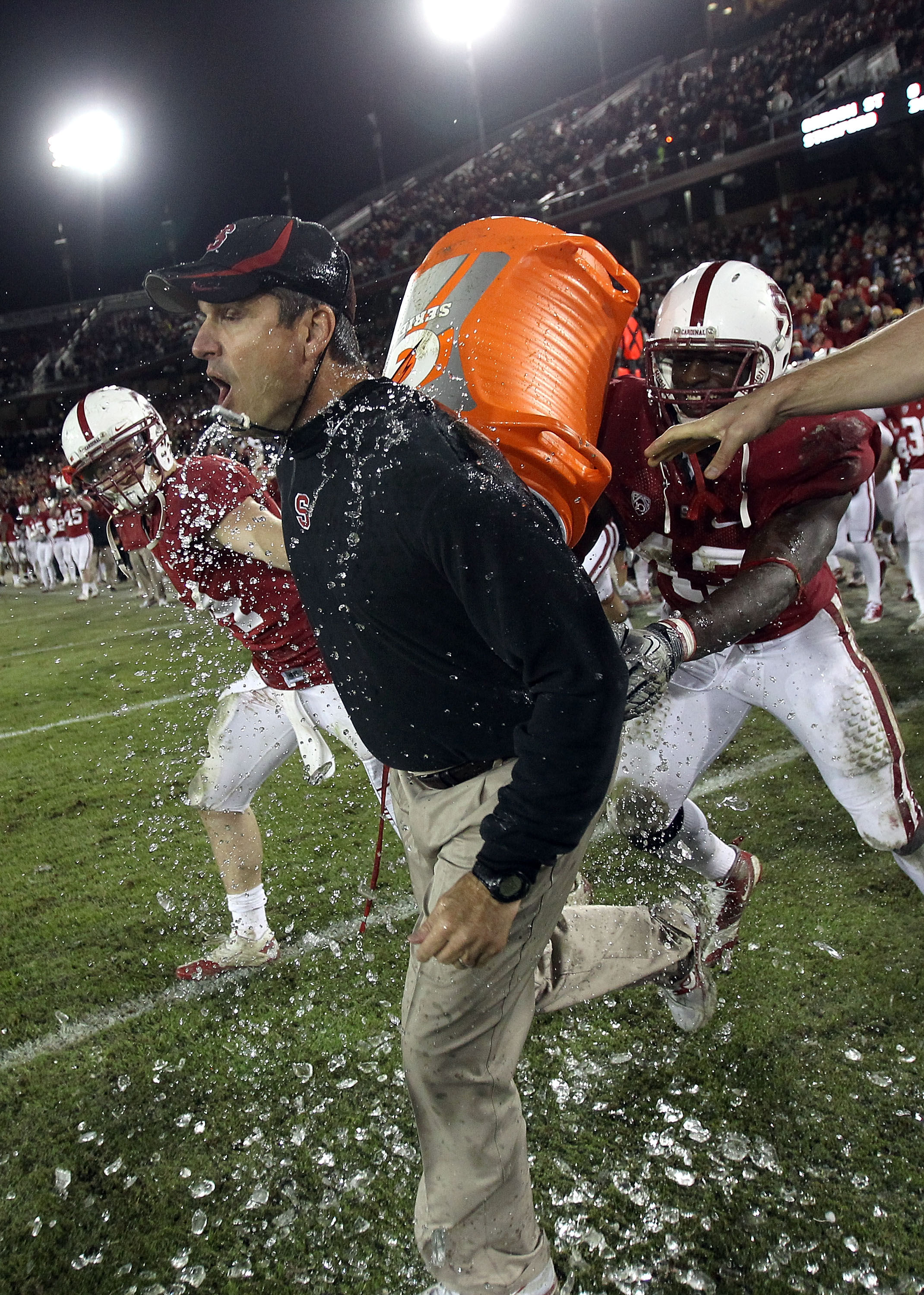 PALO ALTO, CA - NOVEMBER 27:  Head coach Jim Harbaugh of the Stanford Cardinal is covered with water from a Gatorade cooler by Andrew Luck #12 and Chike Amajoyi #43 after the Cardinal beat the Oregon State Beavers at Stanford Stadium on November 27, 2010