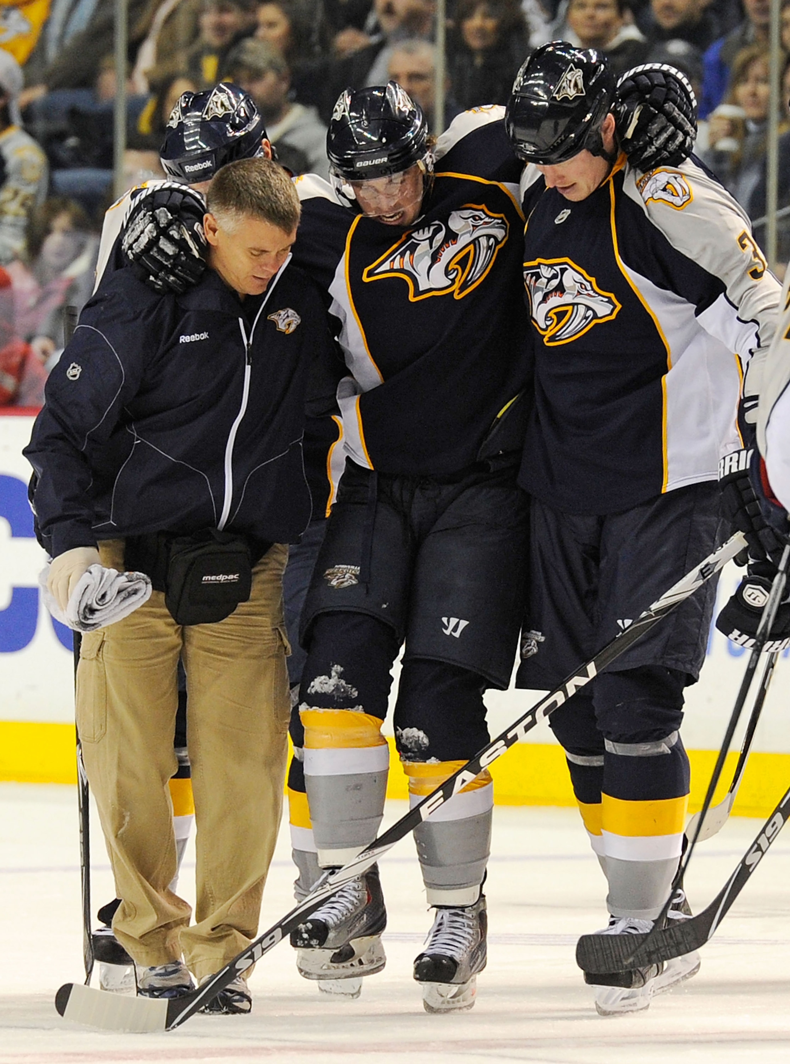NASHVILLE, TN - JANUARY 02:  Trainer Dan Redman and right wing Wade Belak #3 of the Nashville Predators carrie Cal O'Reilly #16 off the ice after an being injured against the Columbus Blue Jackets on January 2, 2011 at the Bridgestone Arena in Nashville,