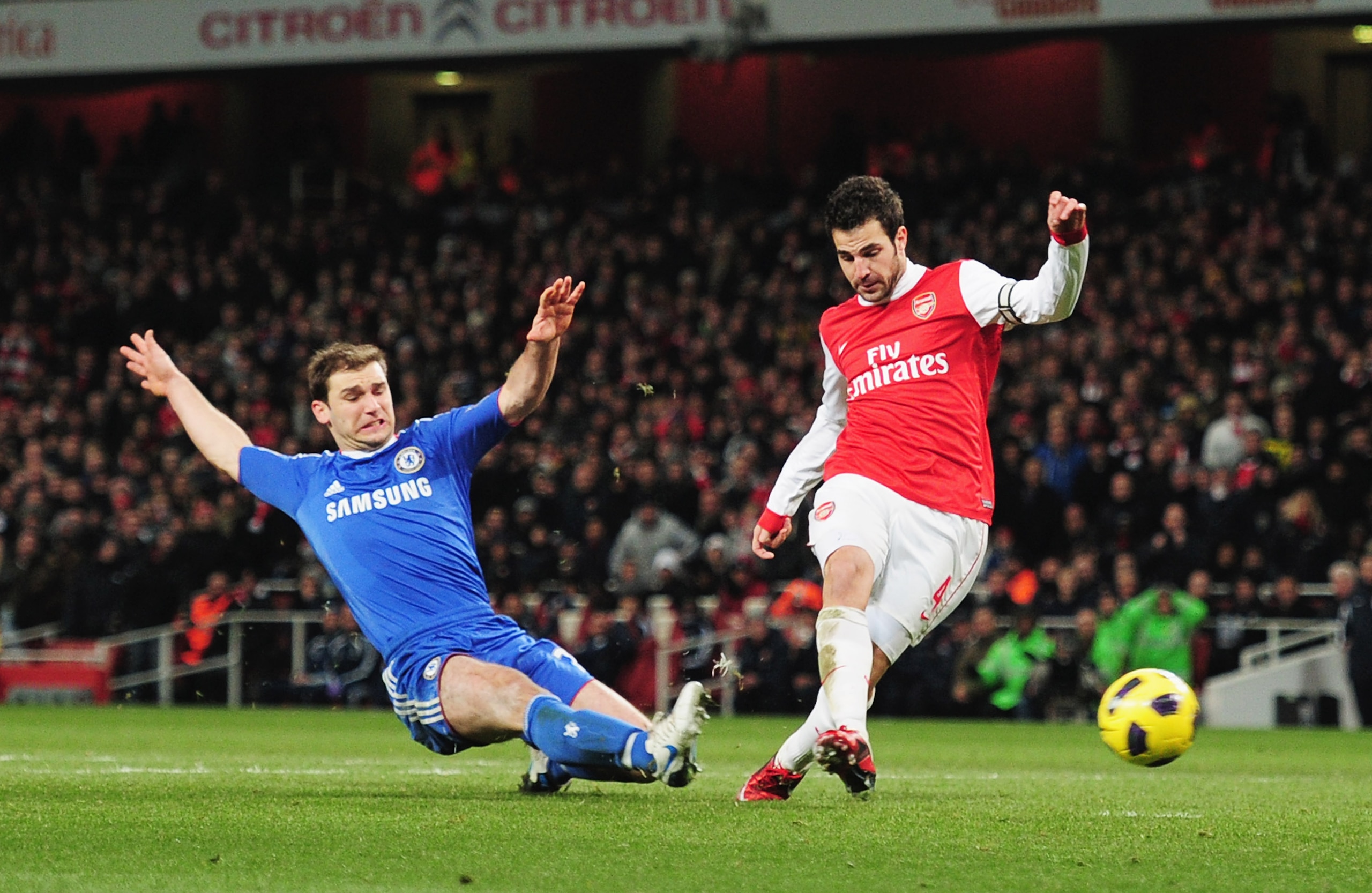 LONDON, ENGLAND - DECEMBER 27:  Cesc Fabregas of Arsenal shoots to score Arsenal's second goal despite a challenge by Branislav Ivanovic of Chelsea during the Barclays Premier League match between Arsenal and Chelsea at the Emirates Stadium on December 27