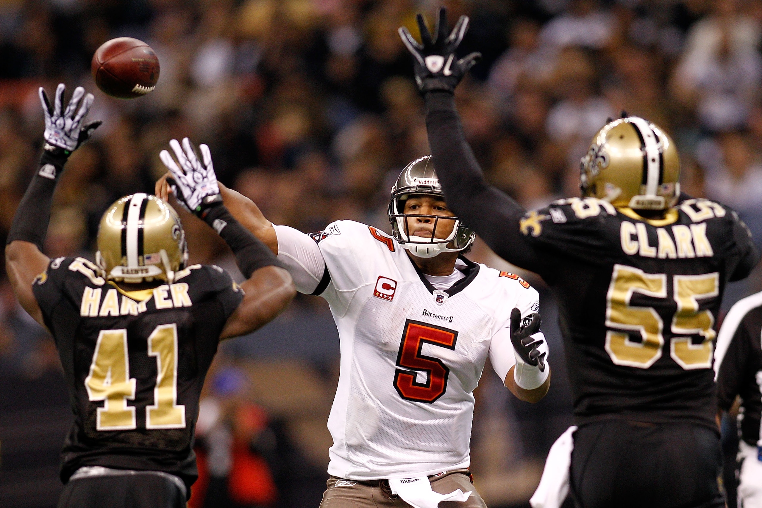 NEW ORLEANS, LA - JANUARY 02:  Quarterback Josh Freeman #5 of the Tampa Bay Buccaneers throws a pass over Roman Harper #41 and Danny Clark #55  of the New Orleans Saints at the Louisiana Superdome on January 2, 2011 in New Orleans, Louisiana.   The Buccan