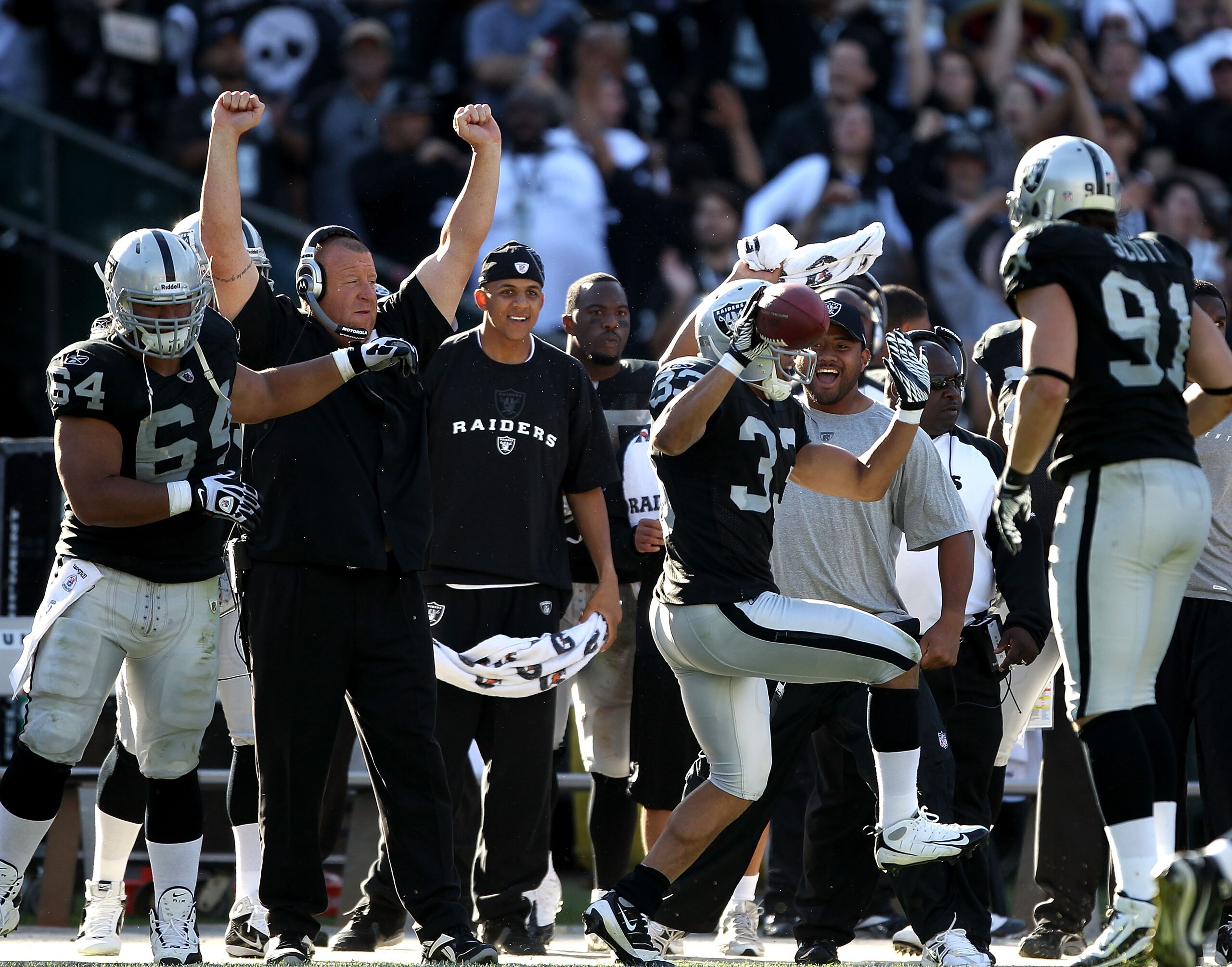 OAKLAND, CA - OCTOBER 31: Head coach Tom Cable of the Oakland Raiders celebrates with his arms in the air while Tyvon Branch #33 runs back an interception against the Seattle Seahawks at Oakland-Alameda County Coliseum on October 31, 2010 in Oakland, Cali