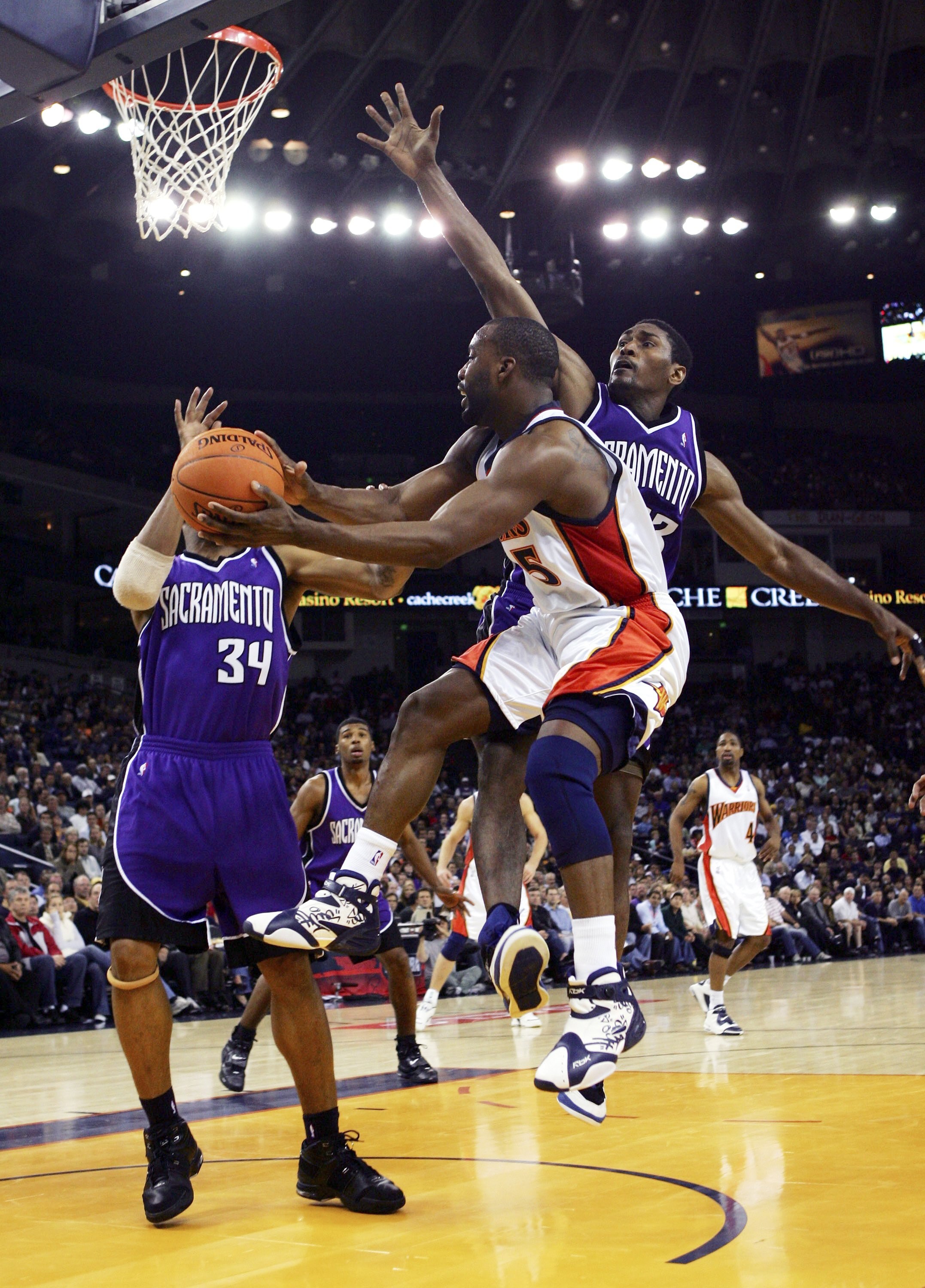 OAKLAND, CA - NOVEMBER 16:  Baron Davis #5 of the Golden State Warriors passes over Ron Artest #93 of the Sacramento Kings on November 16, 2006 at Oracle Arena in Oakland, California. NOTE TO USER: User expressly acknowledges and agrees that, by downloadi