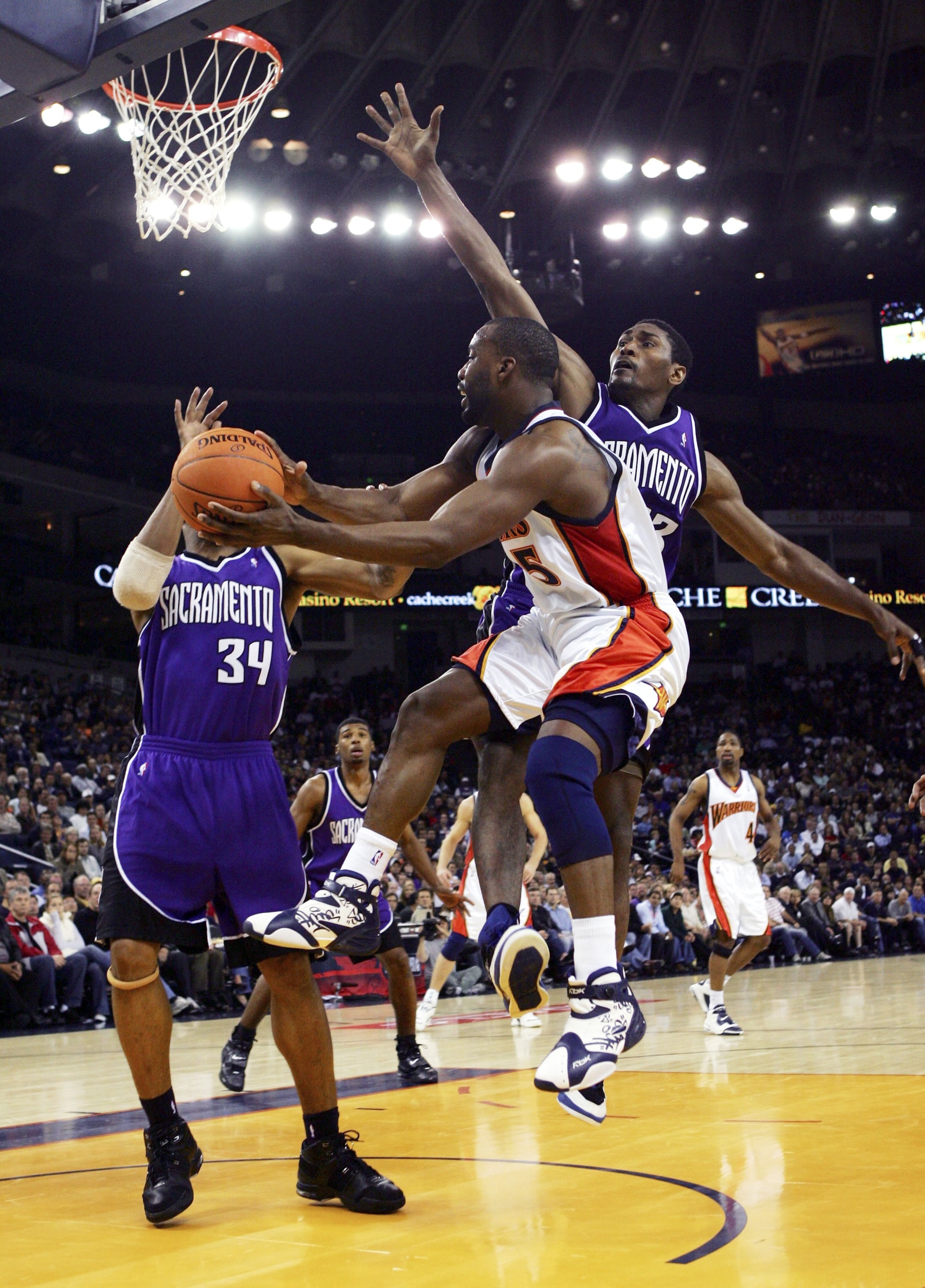 OAKLAND, CA - NOVEMBER 16:  Baron Davis #5 of the Golden State Warriors passes over Ron Artest #93 of the Sacramento Kings on November 16, 2006 at Oracle Arena in Oakland, California. NOTE TO USER: User expressly acknowledges and agrees that, by downloadi