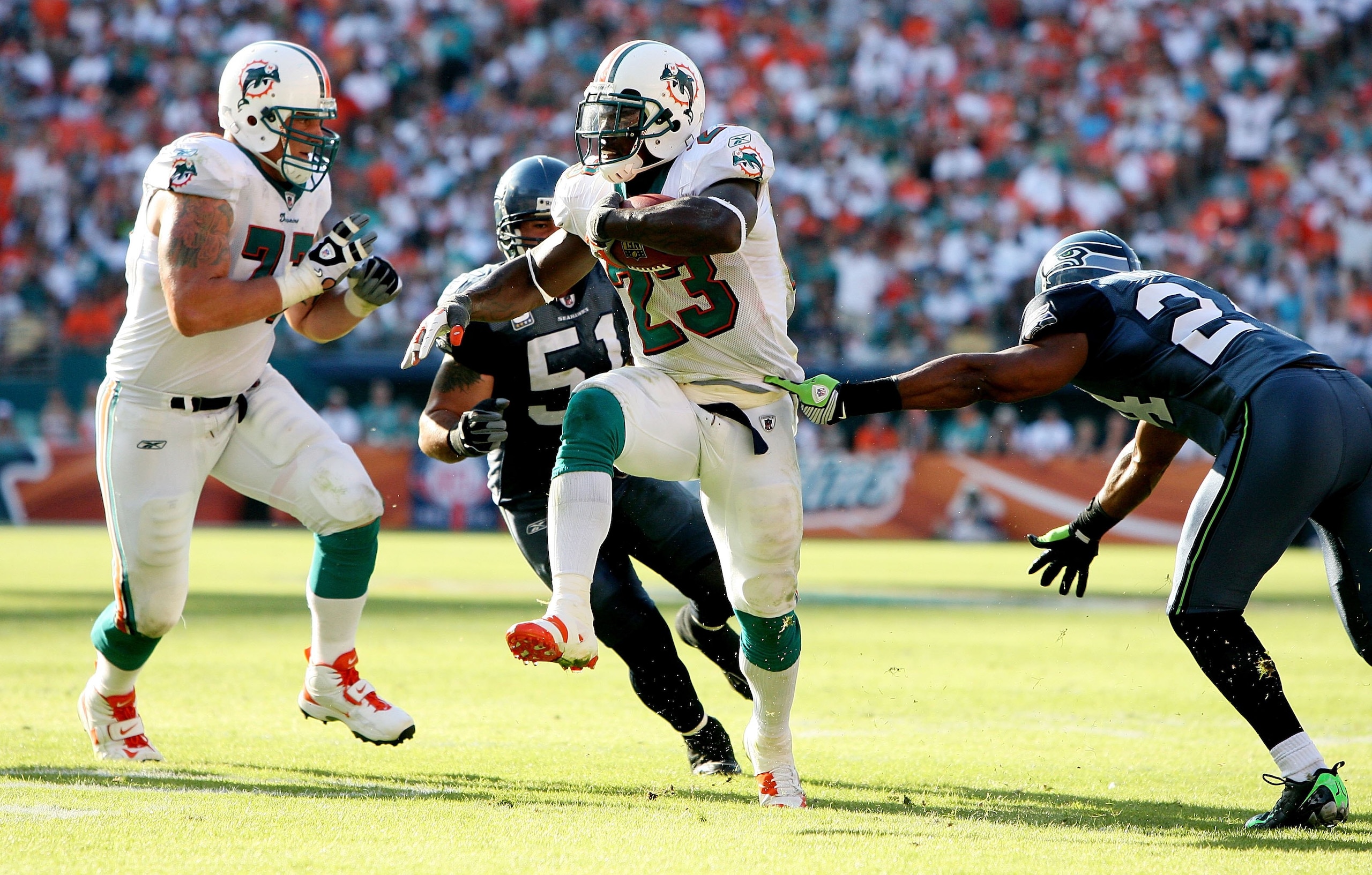 MIAMI - NOVEMBER 09:  Running back Ronnie Brown #23 of the Miami Dolphins shakes a tackle attempt by safety Deon Grant #24 of the Seattle Seahawks to score a fourth quarter touchdown at Dolphin Stadium on November 9, 2008 in Miami, Florida. The Dolphins d