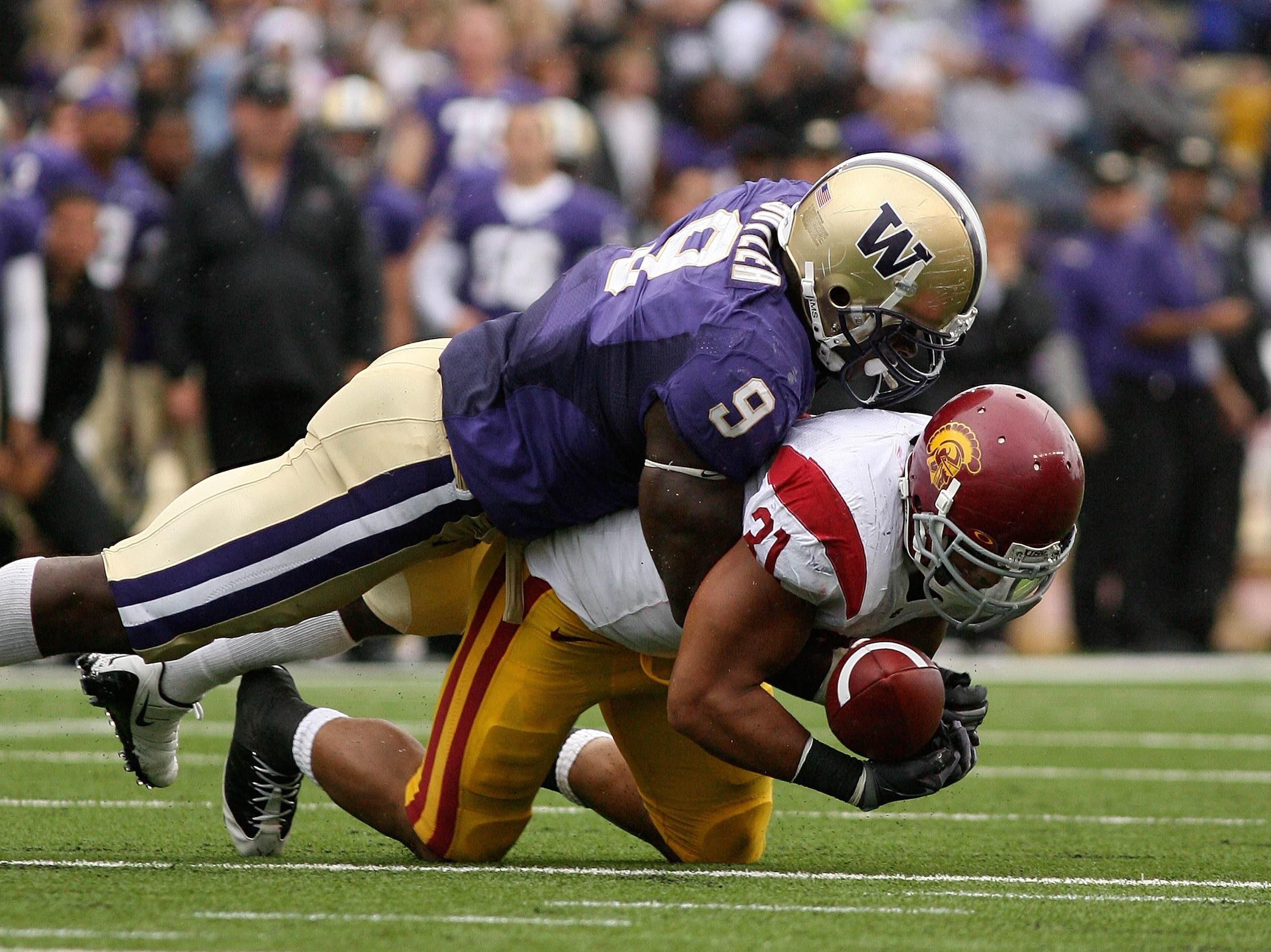 SEATTLE - SEPTEMBER 19:  Running back Stanley Havili #31 of the USC Trojans fumbles against Donald Butler #9 of the Washington Huskies in the third quarter on September 19, 2009 at Husky Stadium in Seattle, Washington. The Huskies defeated the Trojans 16-