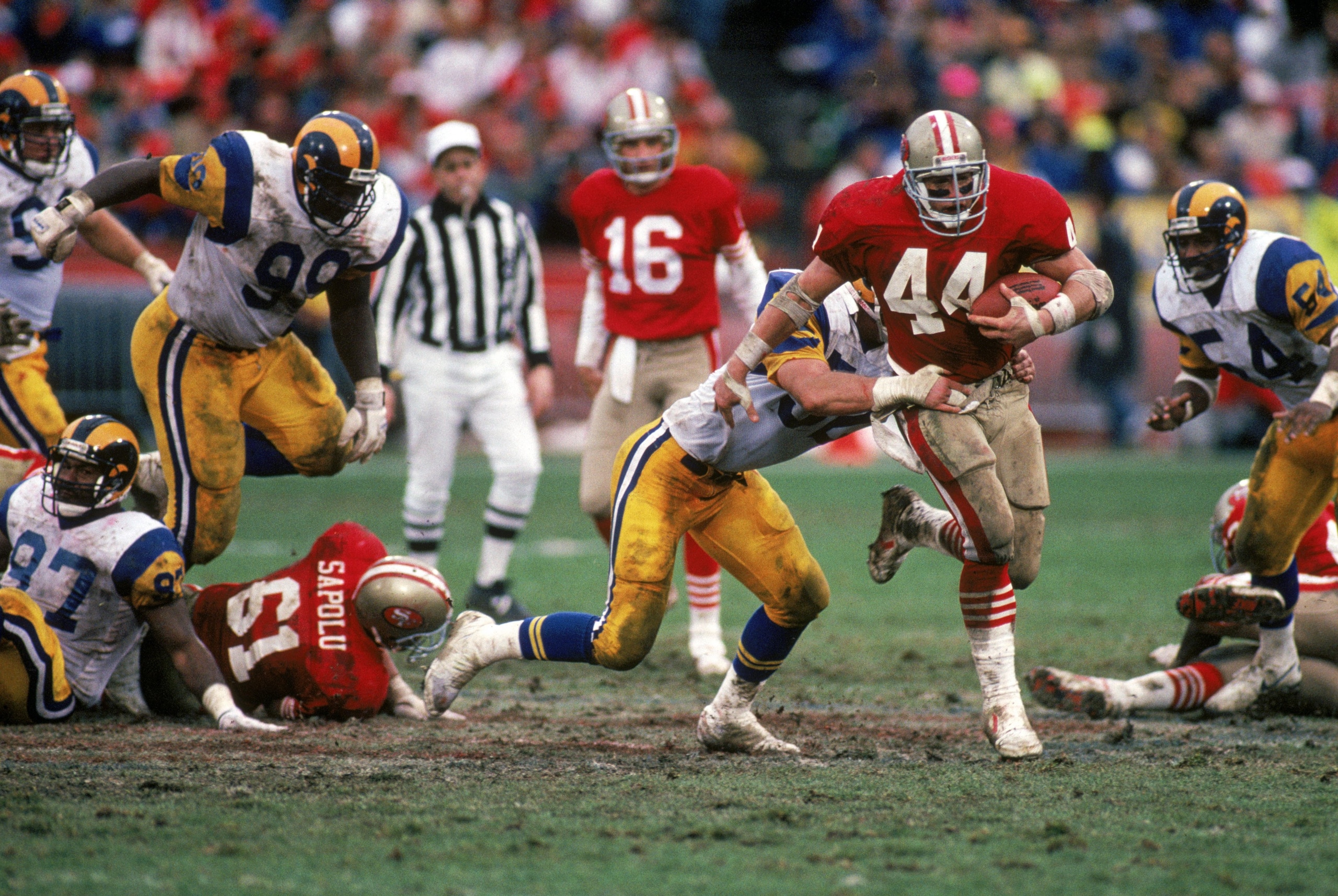 SAN FRANCISCO - JANUARY 14:  Full back Tom Rathman #44 of the San Francisco 49ers tries to break a tackle by Los Angeles Rams linebacker Larry Kelm #52 during the NFC Championship game at Candlestick Park on January 14, 1990 in San Francisco, California.