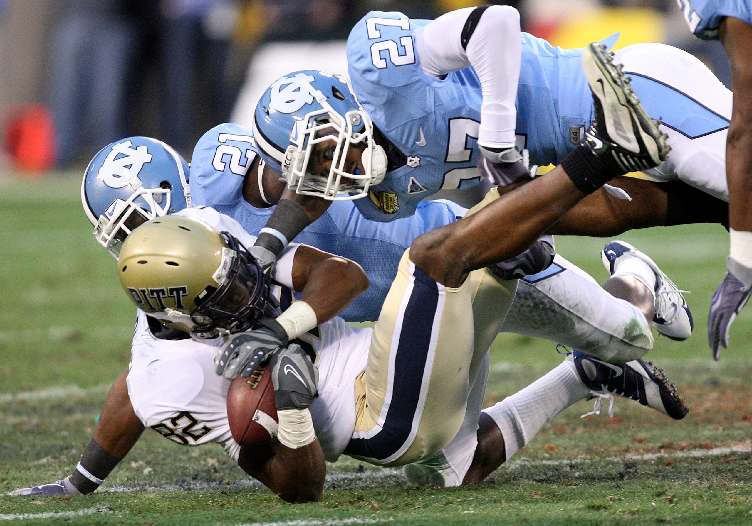 CHARLOTTE, NC - DECEMBER 26:  Jonathan Baldwin #82 of the Pittsburgh Panthers is tackled by teammates Da'Norris Searcy #21 and Deunta Williams #27 of the North Carolina Tar Heels during their game on December 26, 2009 in Charlotte, North Carolina.  (Photo