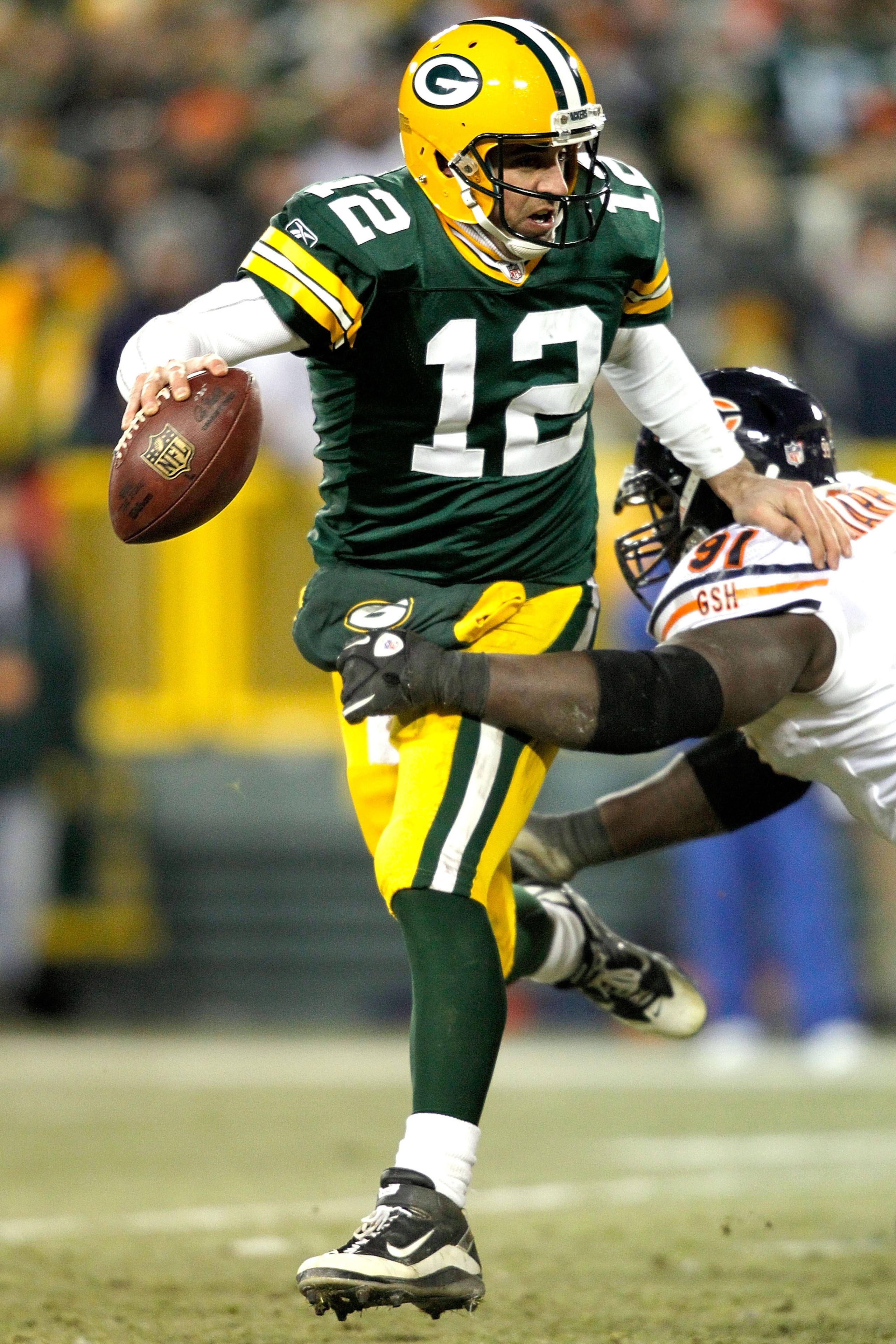 GREEN BAY, WI - JANUARY 02:  Quarterback Aaron Rodgers #12 of the Green Bay Packers attempts to break free from Tommie Harris #91 of the Chicago Bears at Lambeau Field on January 2, 2011 in Green Bay, Wisconsin.  (Photo by Matthew Stockman/Getty Images)