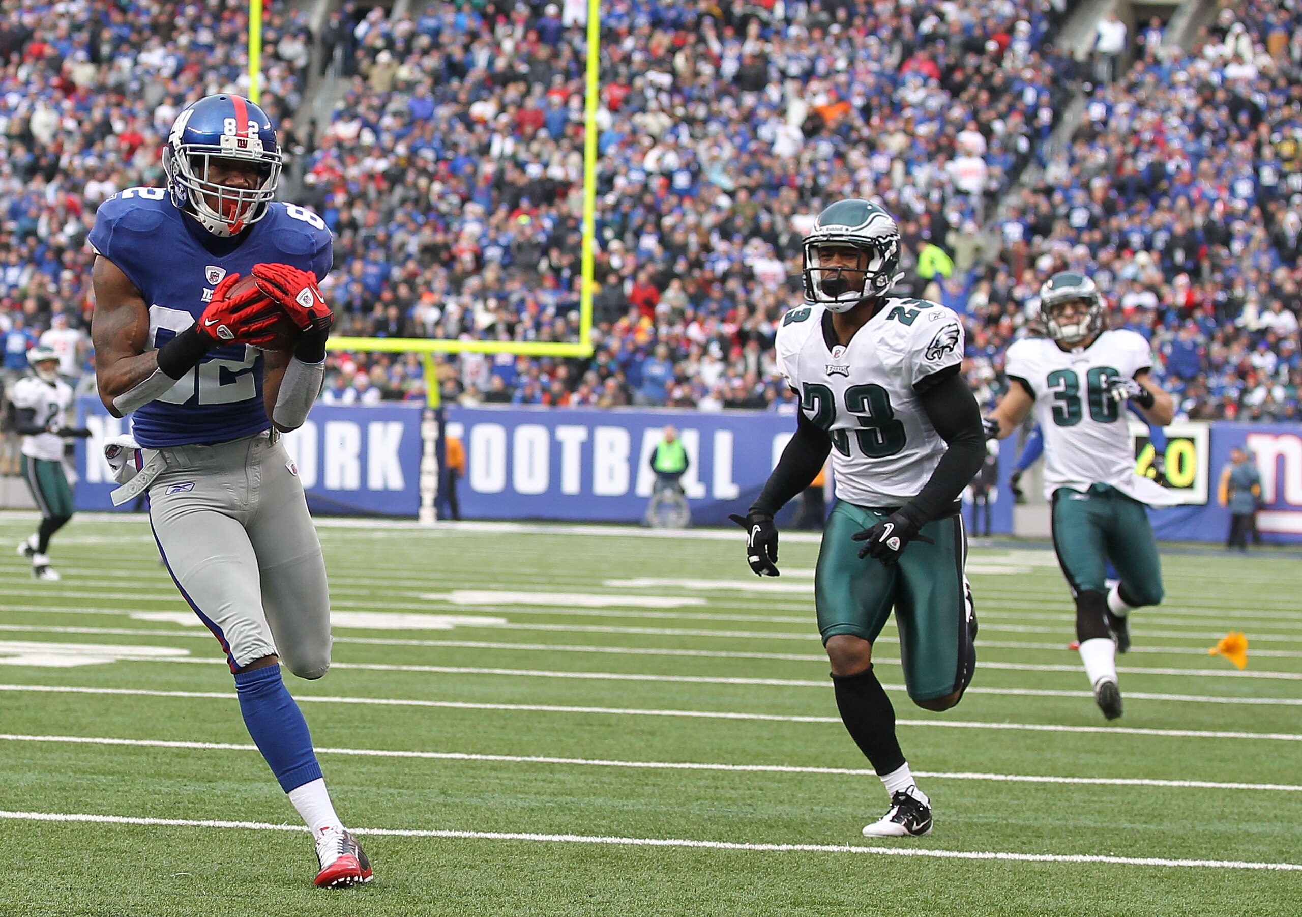 EAST RUTHERFORD, NJ - DECEMBER 19:  Mario Manningham #82 of the New York Giants scores a touchdown in the first quarter as Dimitri Patterson #23 and Colt Anderson #30 of the Philadelphia Eagles defend during their game on December 19, 2010 at The New Mead