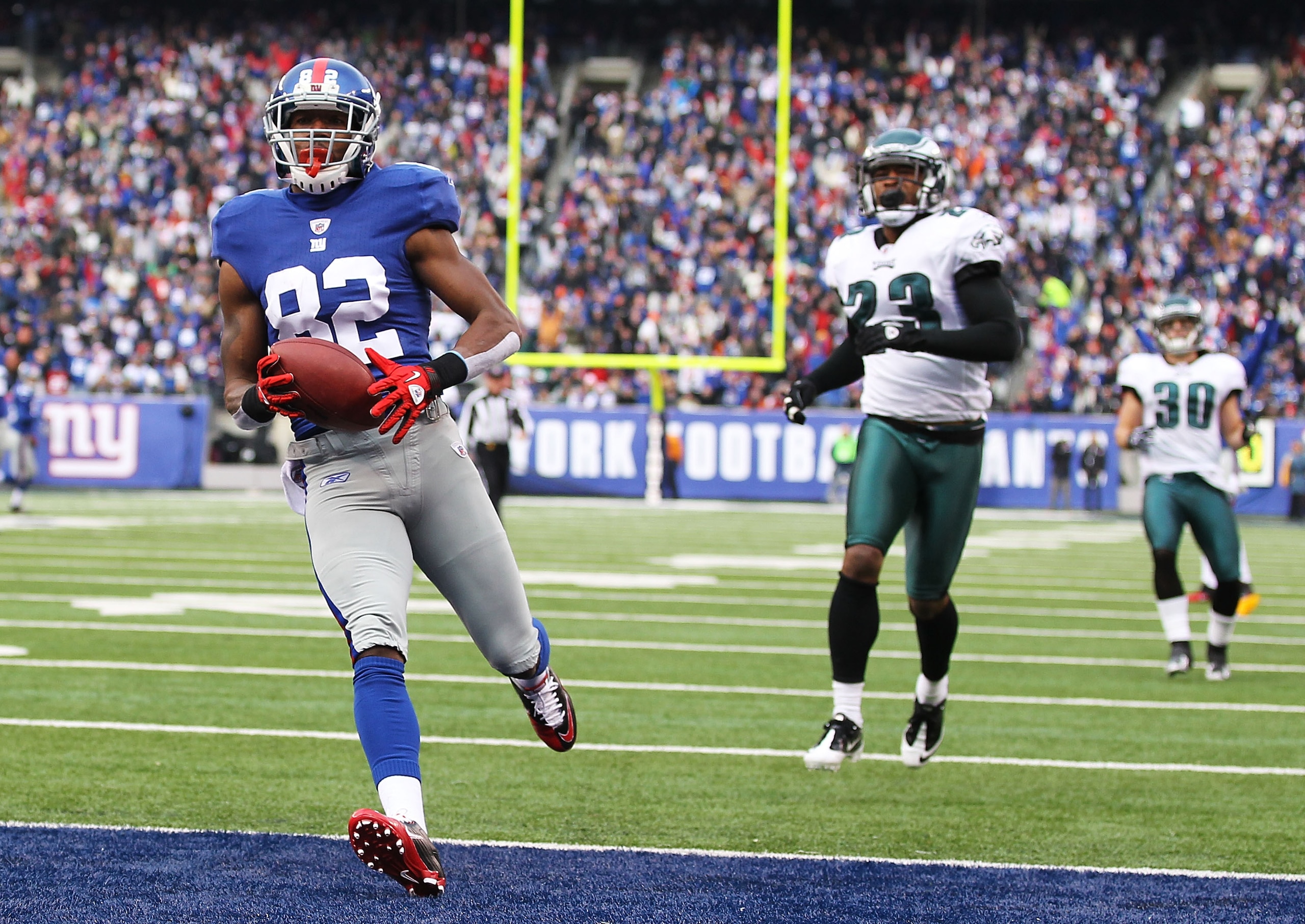 EAST RUTHERFORD, NJ - DECEMBER 19:  Mario Manningham #82 of the New York Giants scores a touchdown in the first quarter as Dimitri Patterson #23 and Colt Anderson #30 of the Philadelphia Eagles defend during their game on December 19, 2010 at The New Mead
