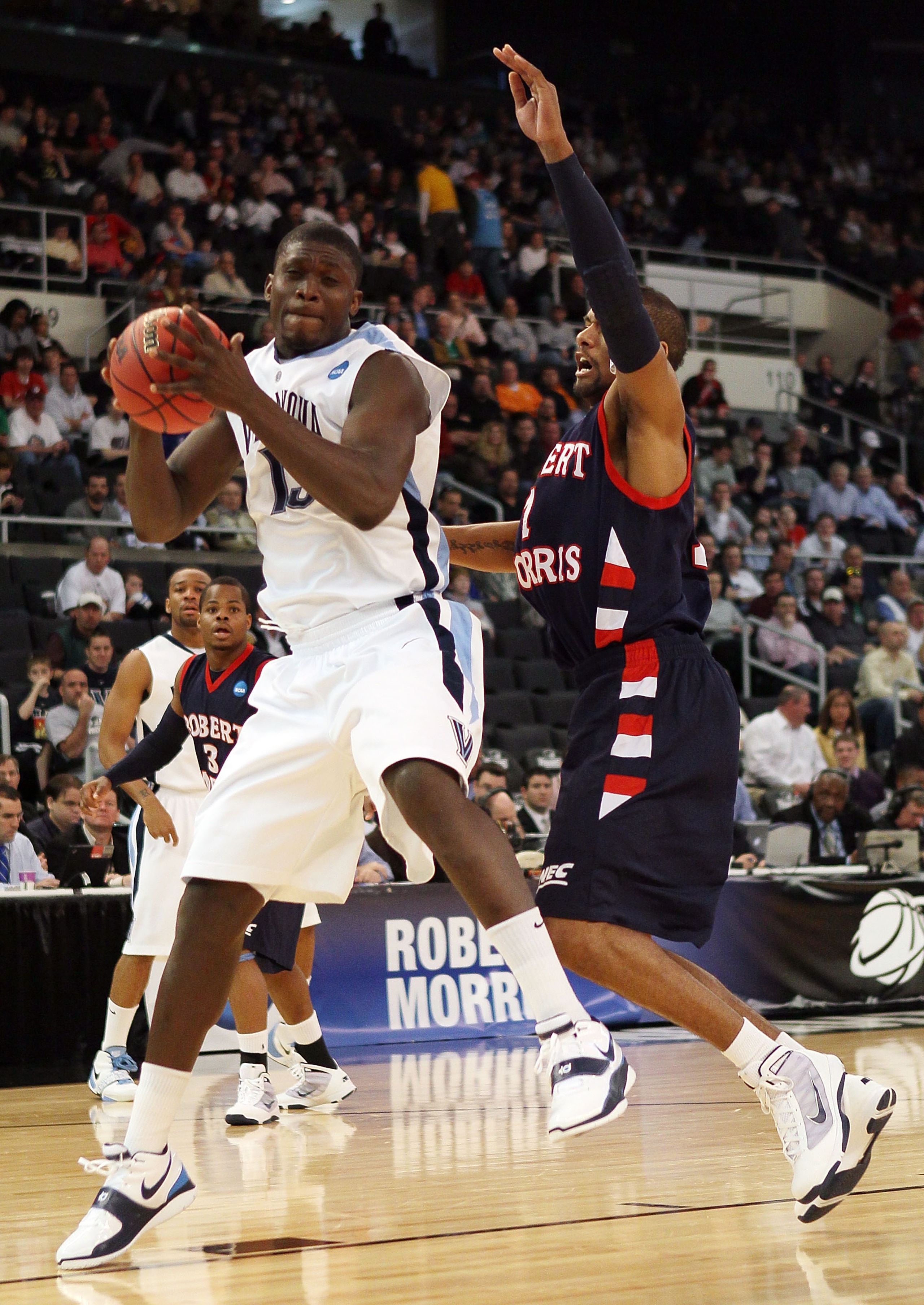 PROVIDENCE, RI - MARCH 18:  Mouphtaou Yarou #13  of the Villanova Wildcats heads for the basket as Rob Robinson #1 of the Robert Morris Colonials defends during the first round of the 2010 NCAA men's basketball tournament on March 18, 2010 at the Dunkin D