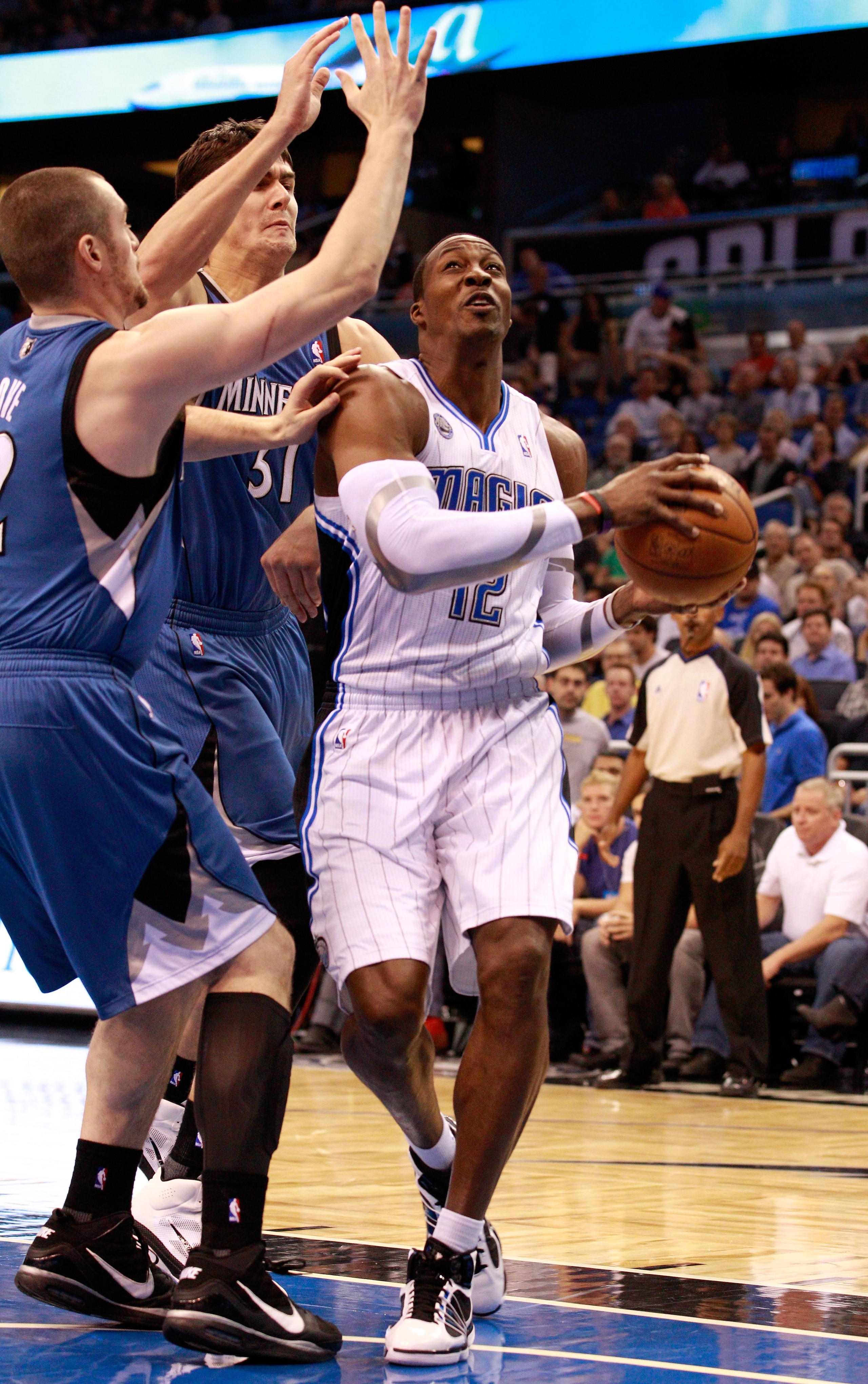 ORLANDO, FL - NOVEMBER 03:  Dwight Howard #12 of the Orlando Migic drives against Darko Milicic #31 and Kevin Love #42 of the Minnesota Timberwolves during the game at Amway Arena on November 3, 2010 in Orlando, Florida.  NOTE TO USER: User expressly ackn