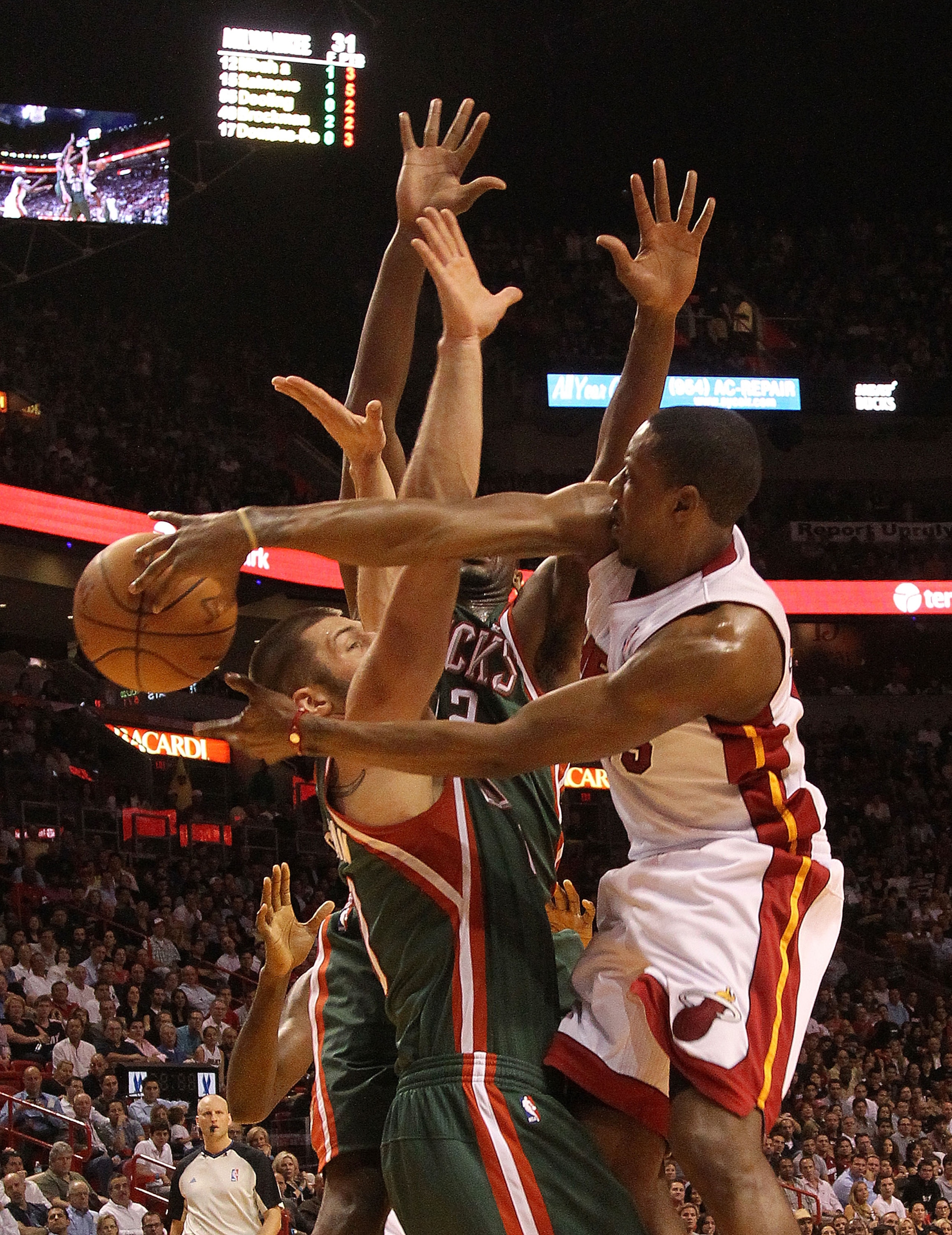 MIAMI, FL - JANUARY 04: Mario Chalmers #15 of the Miami Heat passes the ball over Jon Brockman #40 of the Milwaukee Bucks during a game at American Airlines Arena on January 4, 2011 in Miami, Florida. NOTE TO USER: User expressly acknowledges and agrees t