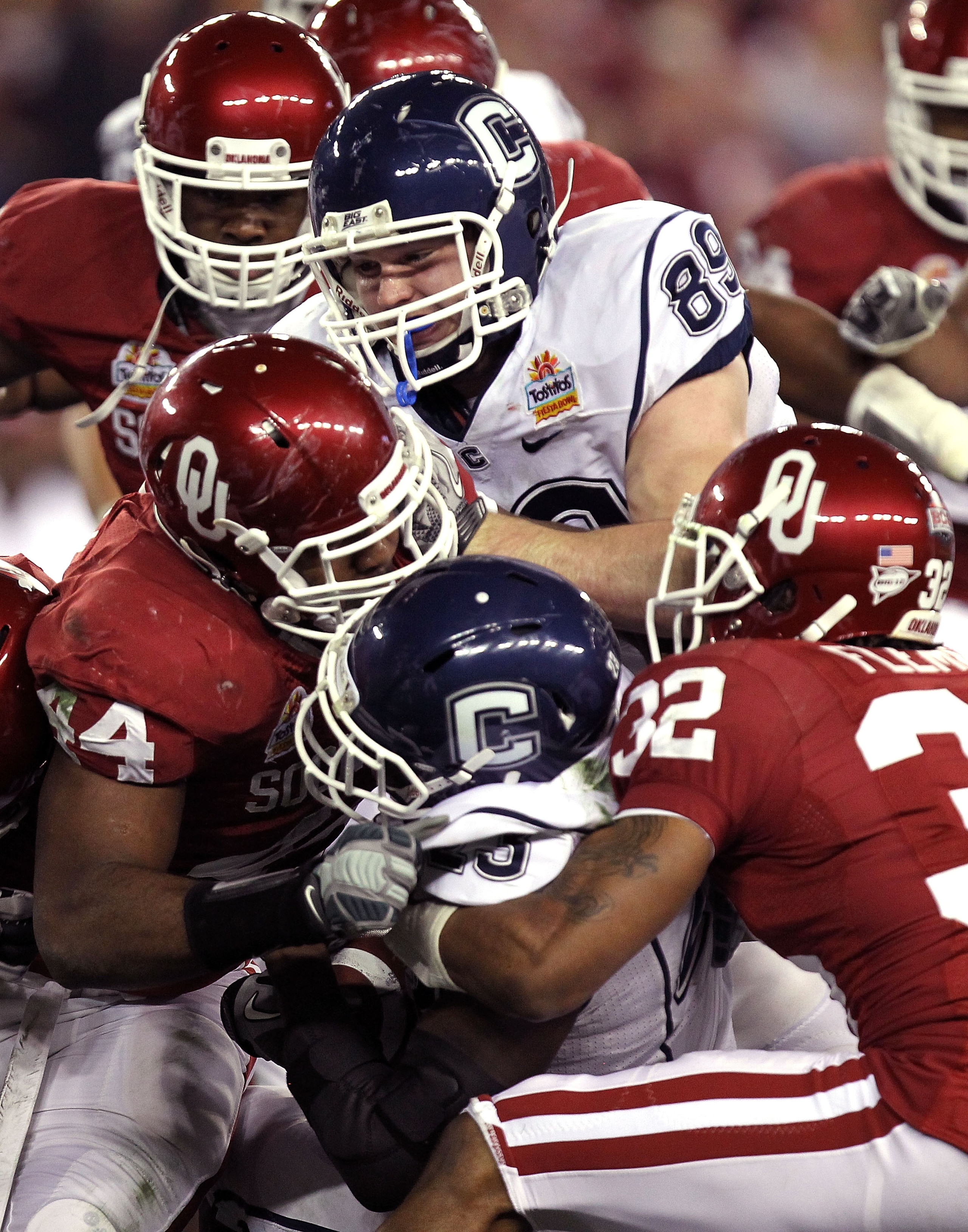 GLENDALE, AZ - JANUARY 01:  Jordan Todman #23 of the Connecticut Huskies is tackled by Jeremy Beal #44 and Jamell Fleming #32 of the Oklahoma Sooners in the first half during the Tostitos Fiesta Bowl at the Universtity of Phoenix Stadium on January 1, 201