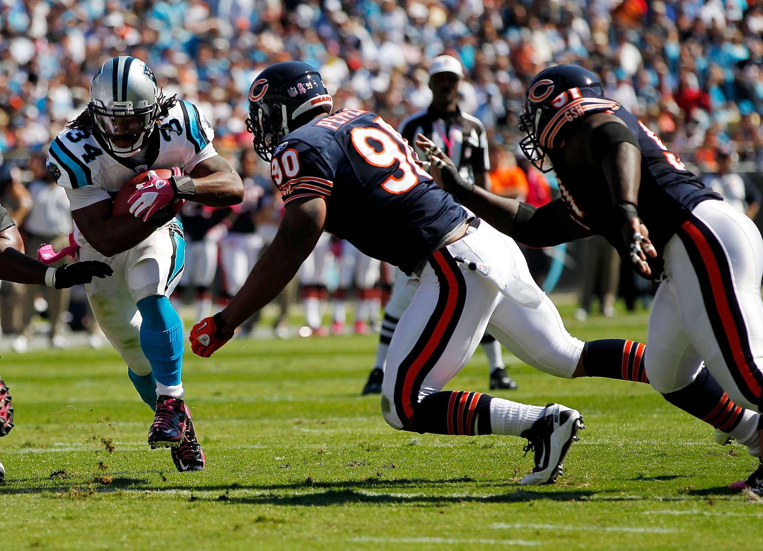 CHARLOTTE, NC - OCTOBER 10: Running back DeAngelo Williams #34 of the Carolina Panthers runs with the ball as defensive end Julius Peppers #90 of the Chicago Bears defends at Bank of America Stadium on October 10, 2010 in Charlotte, North Carolina. (Photo