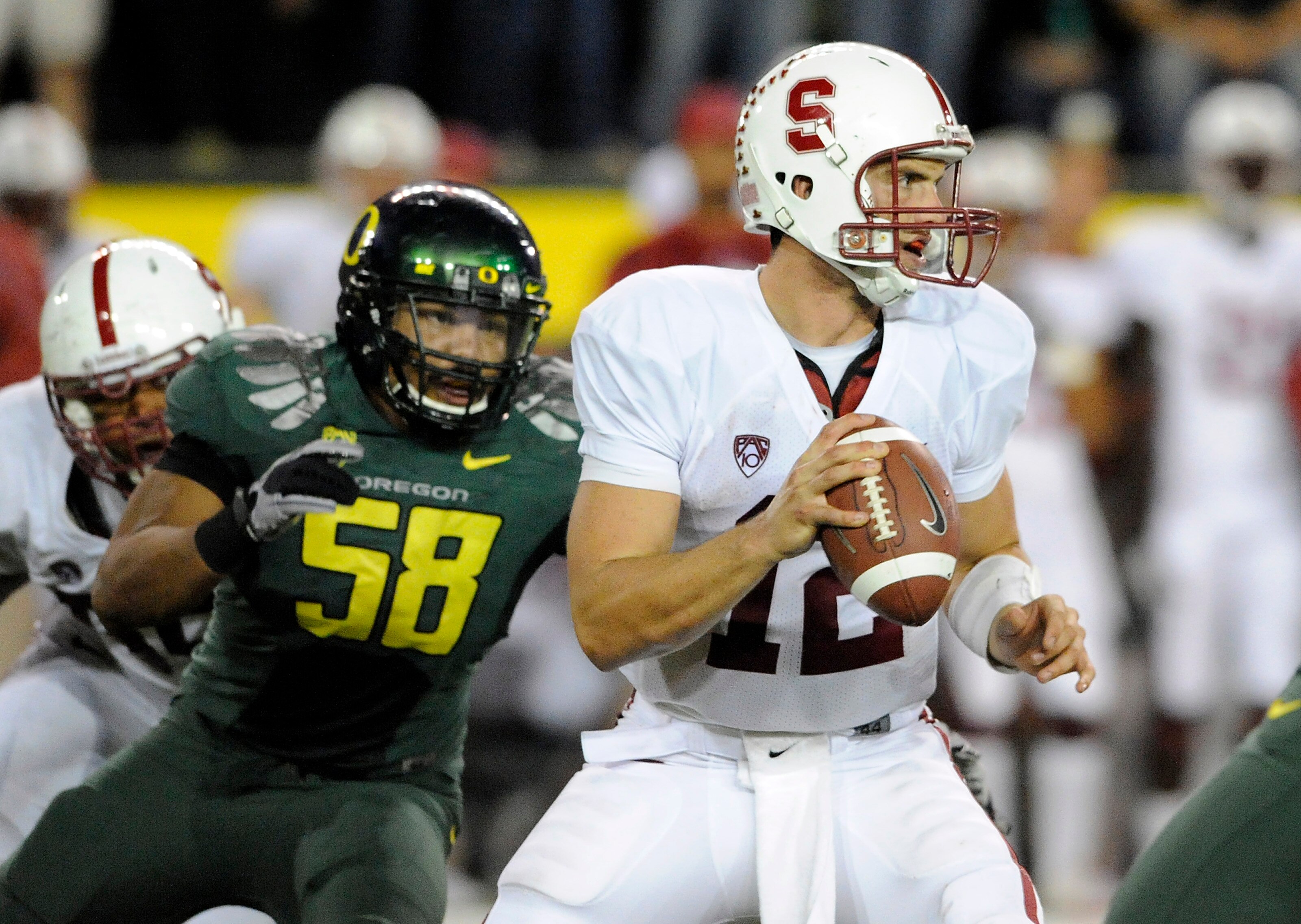 EUGENE, OR - OCTOBER 2: Quarterback Andrew Luck #12 of the Stanford Cardinal is pressured by defensive end Kenny Rowe #58 of the Oregon Ducks in the third quarter of the game at Autzen Stadium on October 2, 2010 in Eugene, Oregon. Oregon won the game 52-3