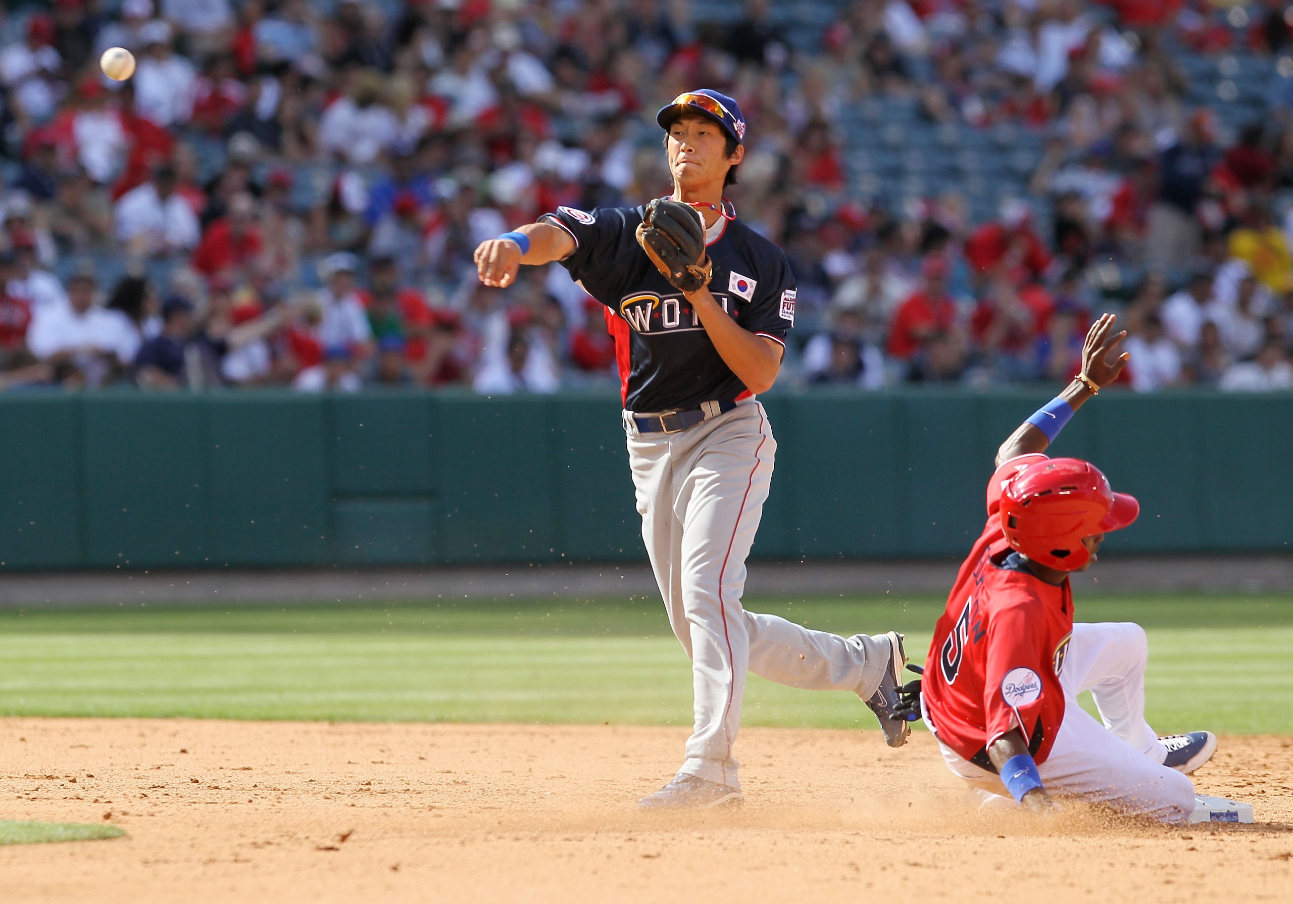 ANAHEIM, CA - JULY 11:  World Futures All-Star Hak-Ju Lee #31 of the Chicago Cubs throws the ball as U.S. Futures All-Star Dee Gordon #5 of the Los Angeles Dodgers slides into base during the 2010 XM All-Star Futures Game at Angel Stadium of Anaheim on Ju
