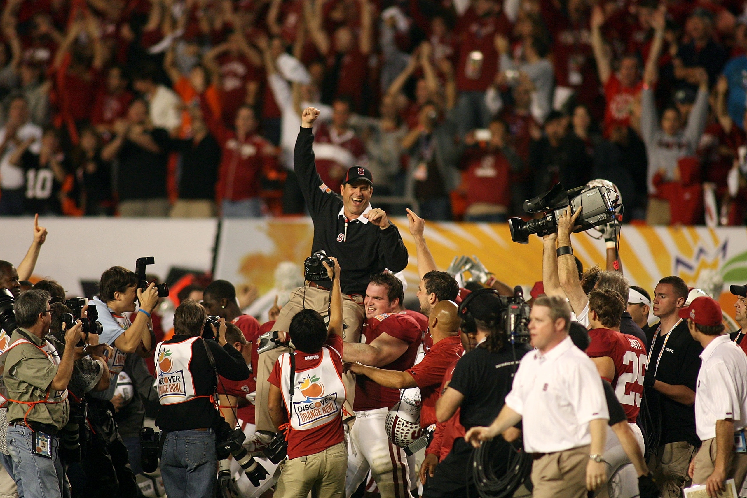 MIAMI, FL - JANUARY 03: Head coach Jim Harbaugh of the Stanford Cardinal is lifted up by his players as they celebrate their 40-12 win against the Virginia Tech Hokies during the 2011 Discover Orange Bowl at Sun Life Stadium on January 3, 2011 in Miami, F
