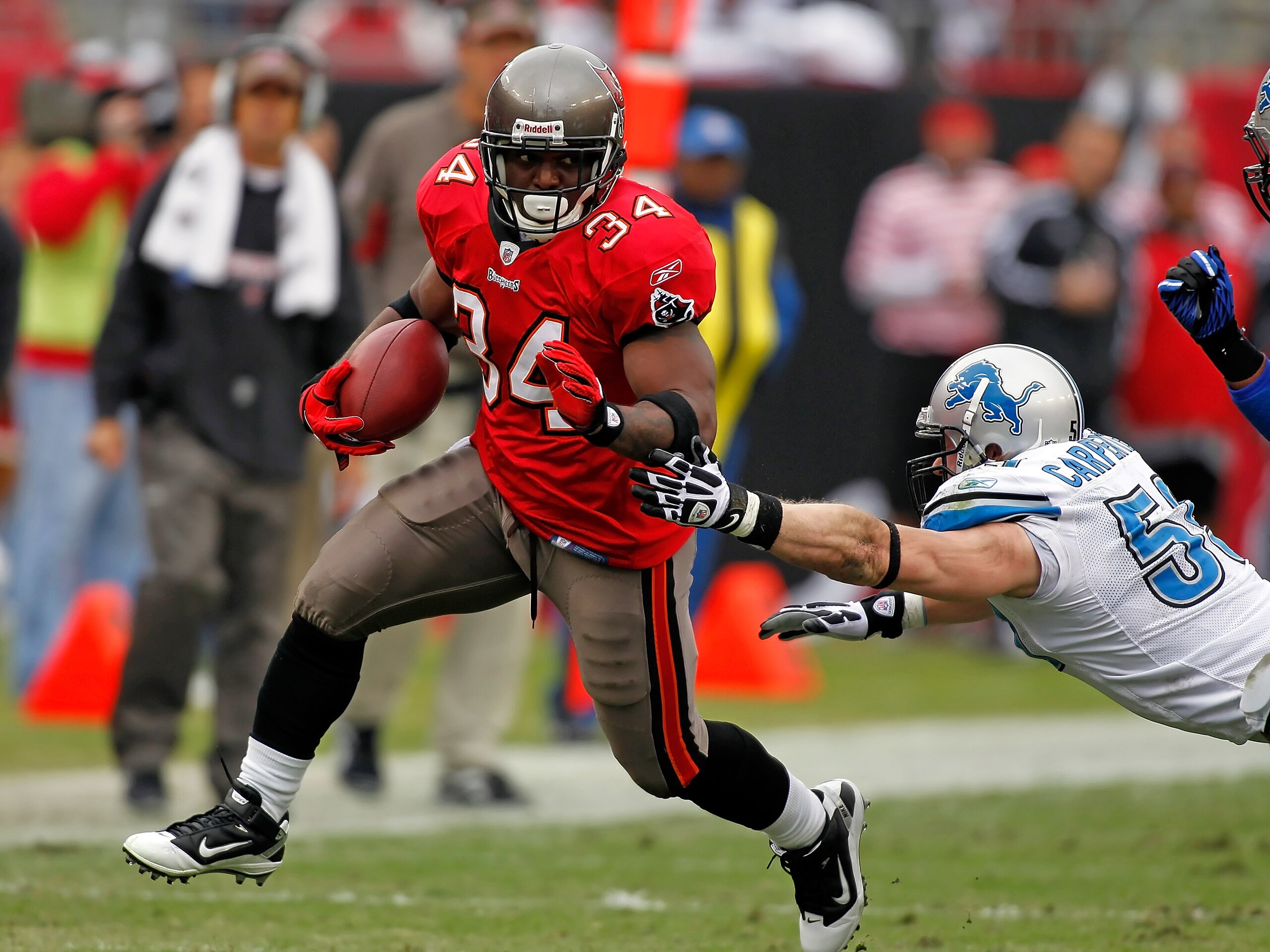 TAMPA, FL - DECEMBER 19:  Running back Earnest Graham #34 of the Tampa Bay Buccaneers runs through the tackle of linebacker Bobby Carpenter #59 of the Detroit Lions during the game at Raymond James Stadium on December 19, 2010 in Tampa, Florida.  (Photo b