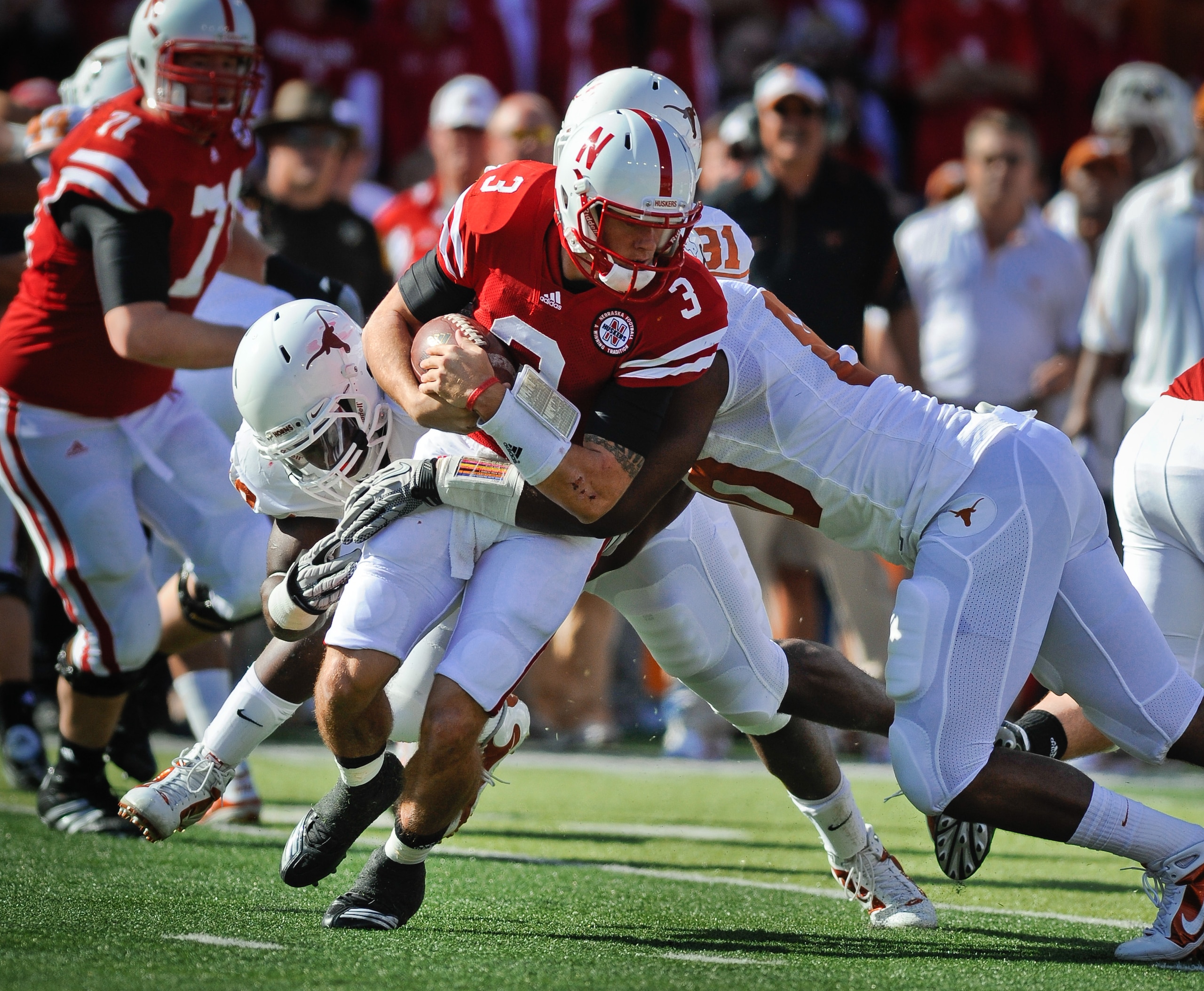 LINCOLN, NE - OCTOBER 16: Quarterback Taylor Martinez #3 of the Nebraska Cornhuskers tries to slip the grasp of defensive end Alex Okafor #80 and linebacker Emmanuel Acho #18 of the Texas Longhorns during first half action of their game at Memorial Stadiu LINCOLN, NE - OCTOBER 16: Quarterback Taylor Martinez #3 of the Nebraska Cornhuskers tries to slip the grasp of defensive end Alex Okafor #80 and linebacker Emmanuel Acho #18 of the Texas Longhorns during first half action of their game at Memorial Stadiu