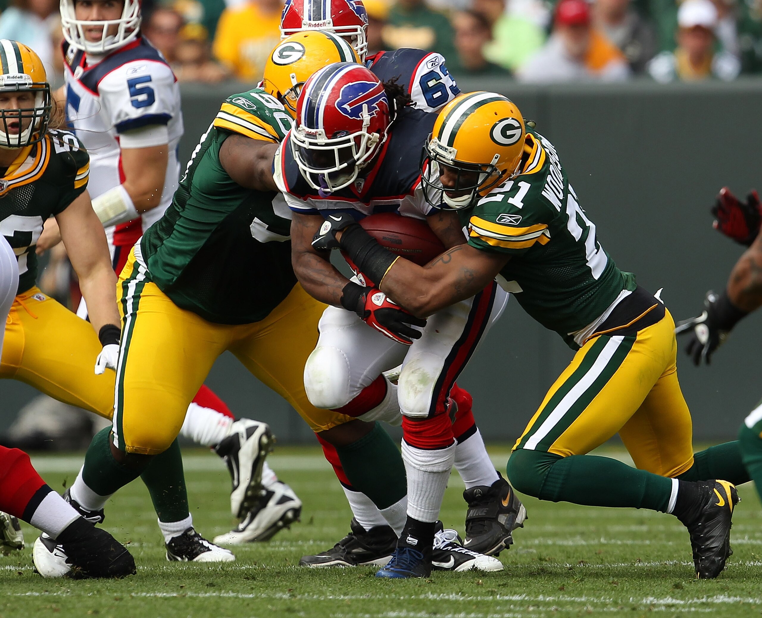 GREEN BAY, WI - SEPTEMBER 19: Marshawn Lynch #23 of the Buffalo Bills is tackled by Charles Woodson #21 and B.J. Raji #90 of the Green Bay Packers at Lambeau Field on September 19, 2010 in Green Bay, Wisconsin. The Packers defeated the Bills 34-7. (Photo