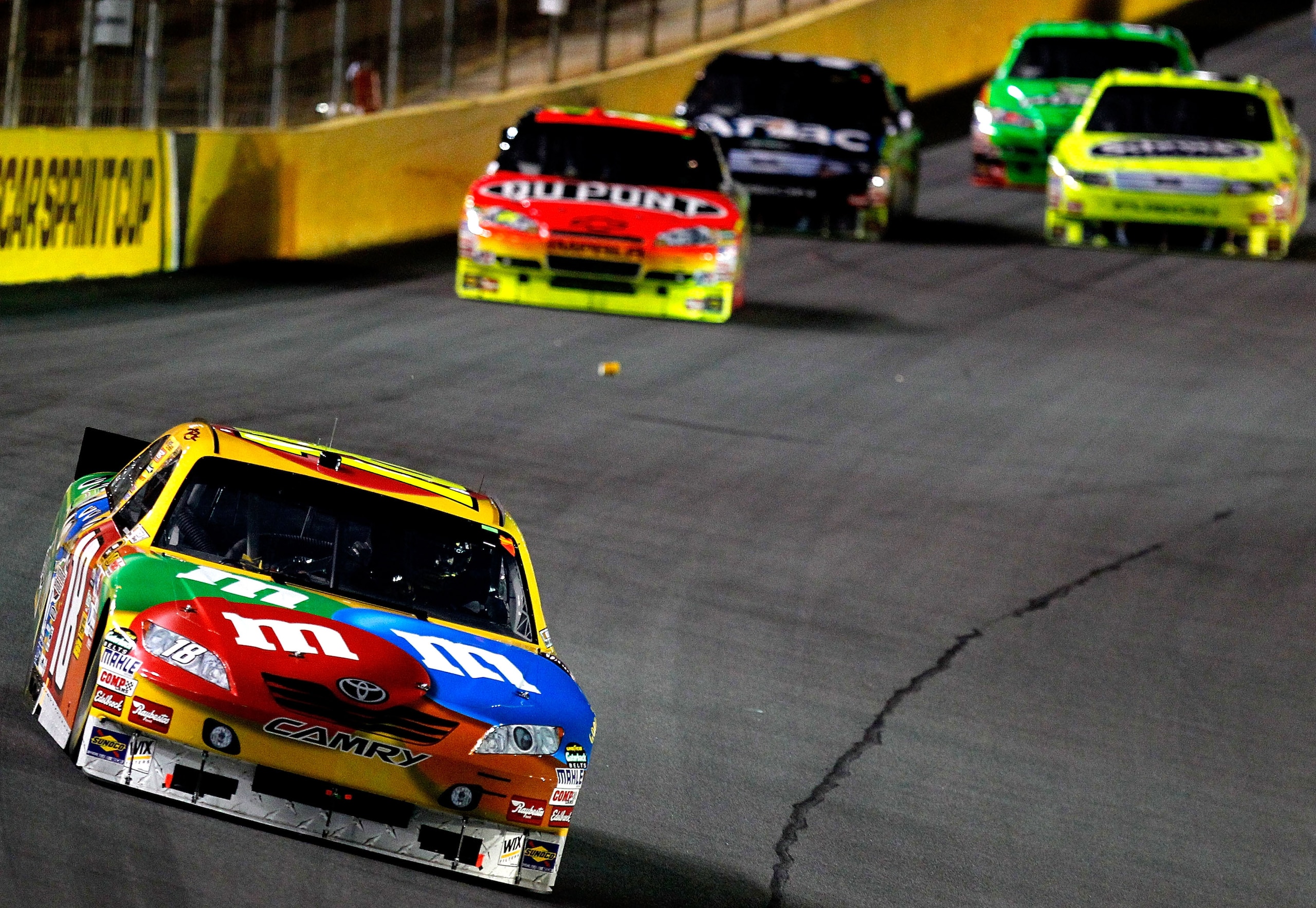 CONCORD, NC - OCTOBER 16:  Kyle Busch, driver of the #18 M&M's Toyota leads Jeff Gordon, driver of the #24 DuPont Chevrolet and others during the NASCAR Sprint Cup Series Bank of America 500 at Charlotte Motor Speedway on October 16, 2010 in Concord, Nort