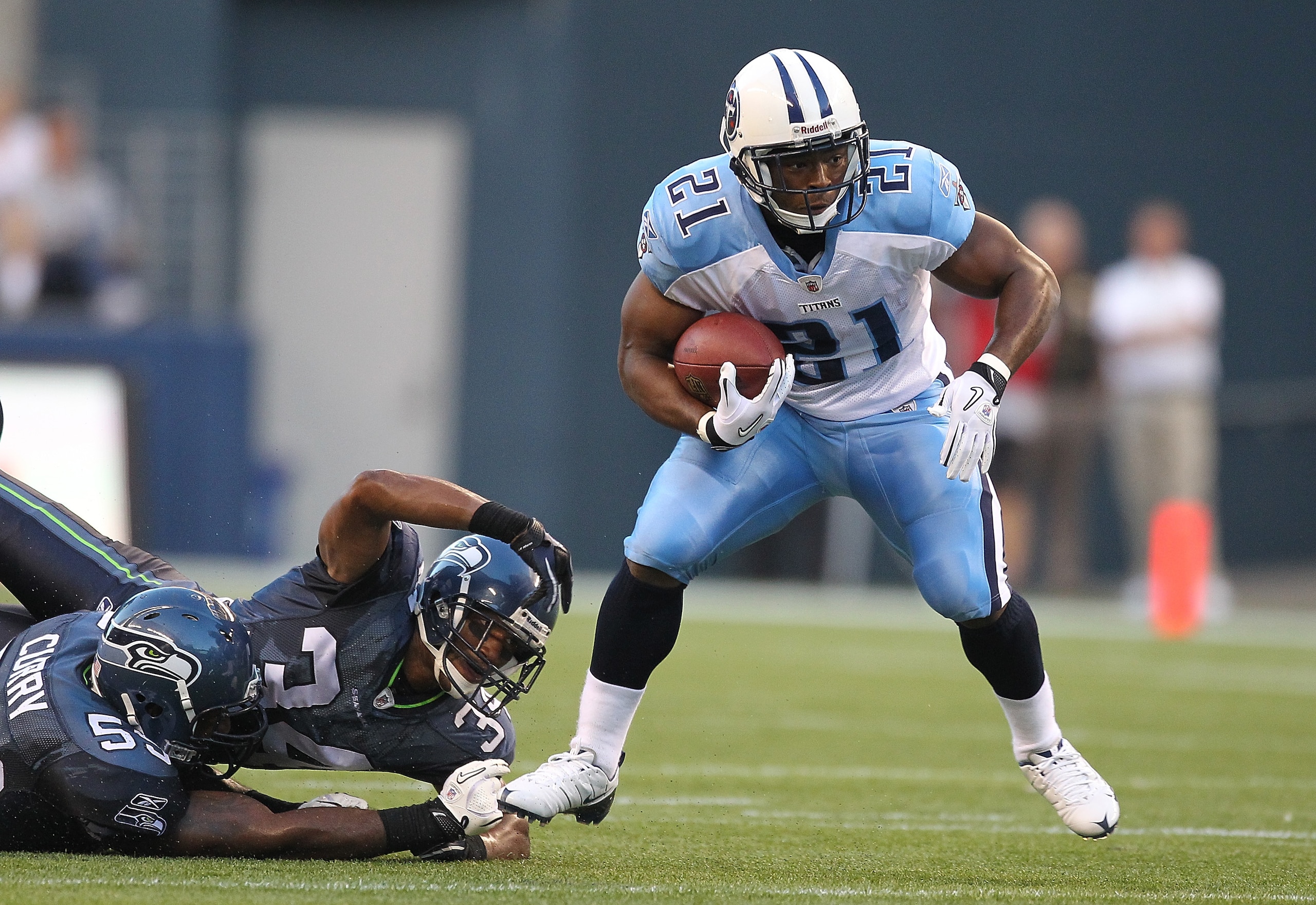 SEATTLE - AUGUST 14:  Running back Javon Ringer #21 of the Tennessee Titans rushes during the preseason game against Roy Lewis #34 and Aaron Curry #59 of the Seattle Seahawks at Qwest Field on August 14, 2010 in Seattle, Washington. The Seahawks defeated
