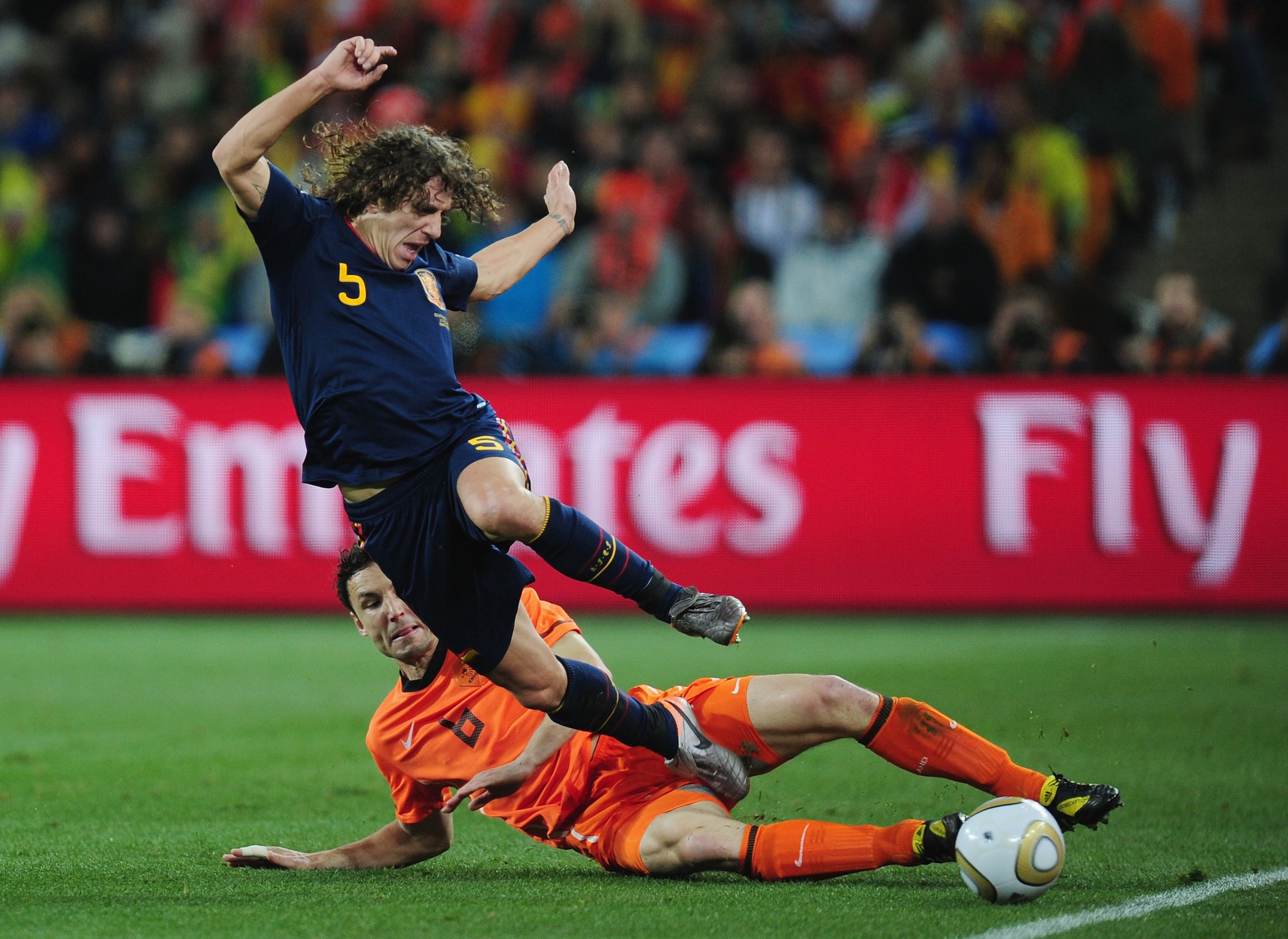 JOHANNESBURG, SOUTH AFRICA - JULY 11: Mark Van Bommel of the Netherlands tackles Carles Puyol of Spain during the 2010 FIFA World Cup South Africa Final match between Netherlands and Spain at Soccer City Stadium on July 11, 2010 in Johannesburg, South Afr