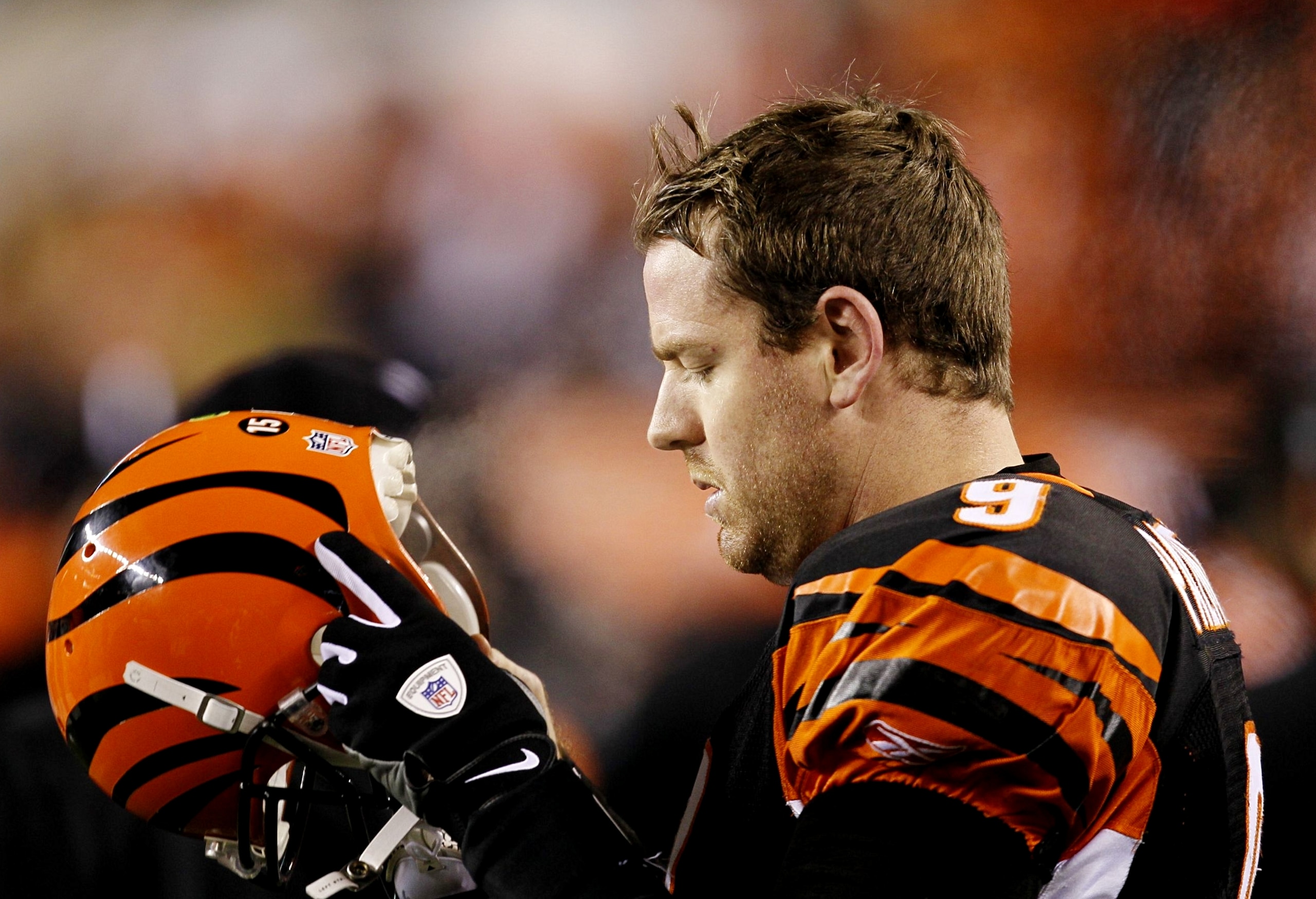 CINCINNATI - JANUARY 9:  Quarterback Carson Palmer #9 of the Cincinnati Bengals looks down at his helmet late in the fourth quarter against the New York Jets during the 2010 AFC wild-card playoff game at Paul Brown Stadium on January 9, 2010 in Cincinnati