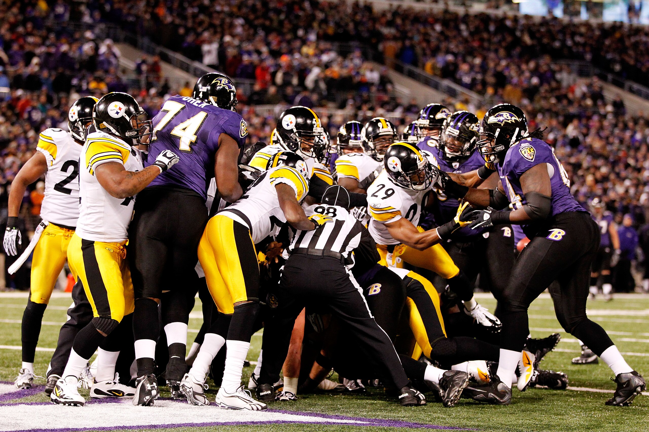 BALTIMORE, MD - DECEMBER 05:  Back judge Greg Steed #12, head linesman Greg Bradley #98 and side judge Michael Banks #72 break up a scuffle between the Baltimore Ravens and the Pittsburgh Steelers during the first quarter of the game at M&T Bank Stadium o
