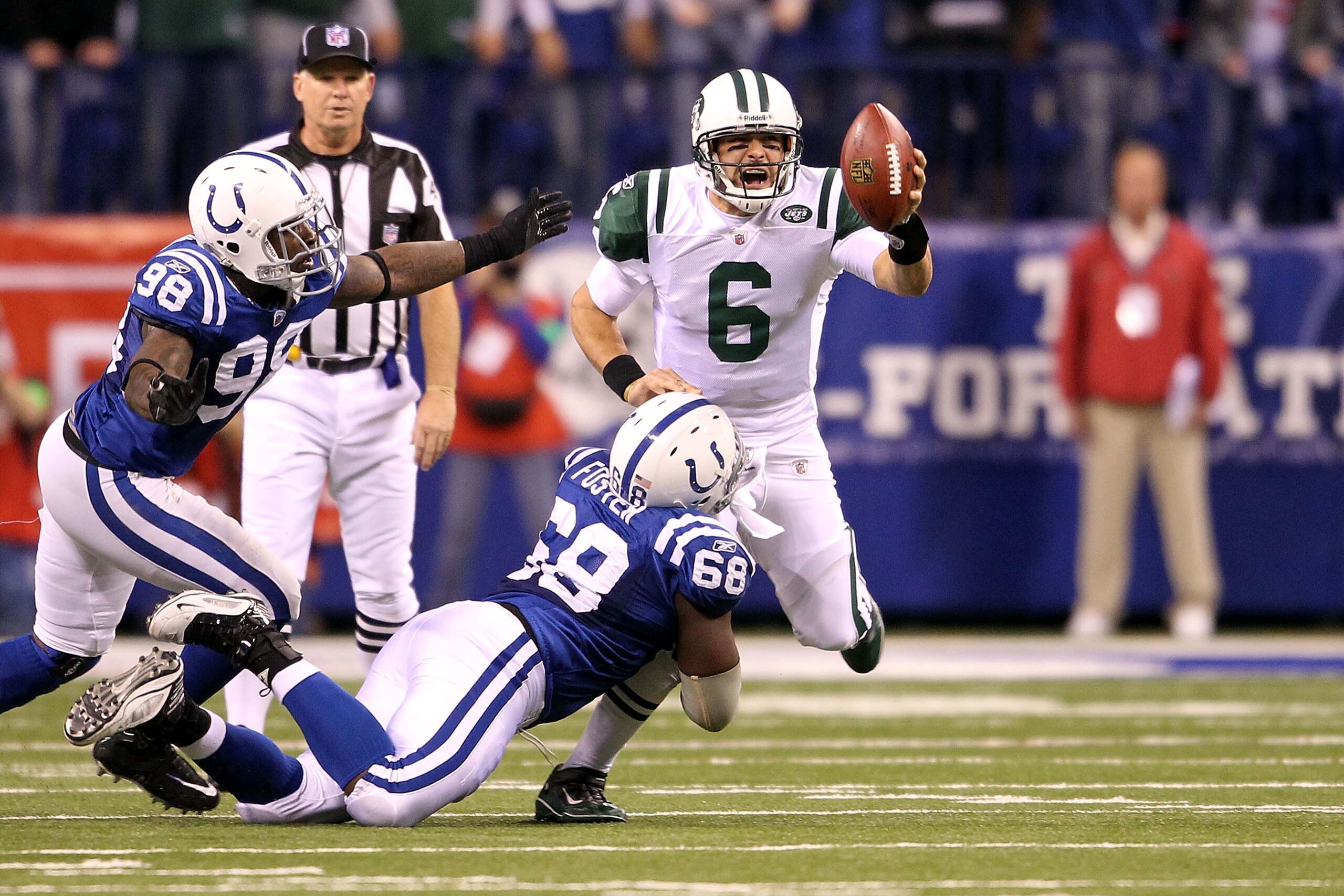 INDIANAPOLIS, IN - JANUARY 08:  Quarterback Mark Sanchez #6 of the New York Jets attempts to escape the pressure by Eric Foster #68 and Robert Mathis #98 of the Indianapolis Colts during their 2011 AFC wild card playoff game at Lucas Oil Stadium on Januar
