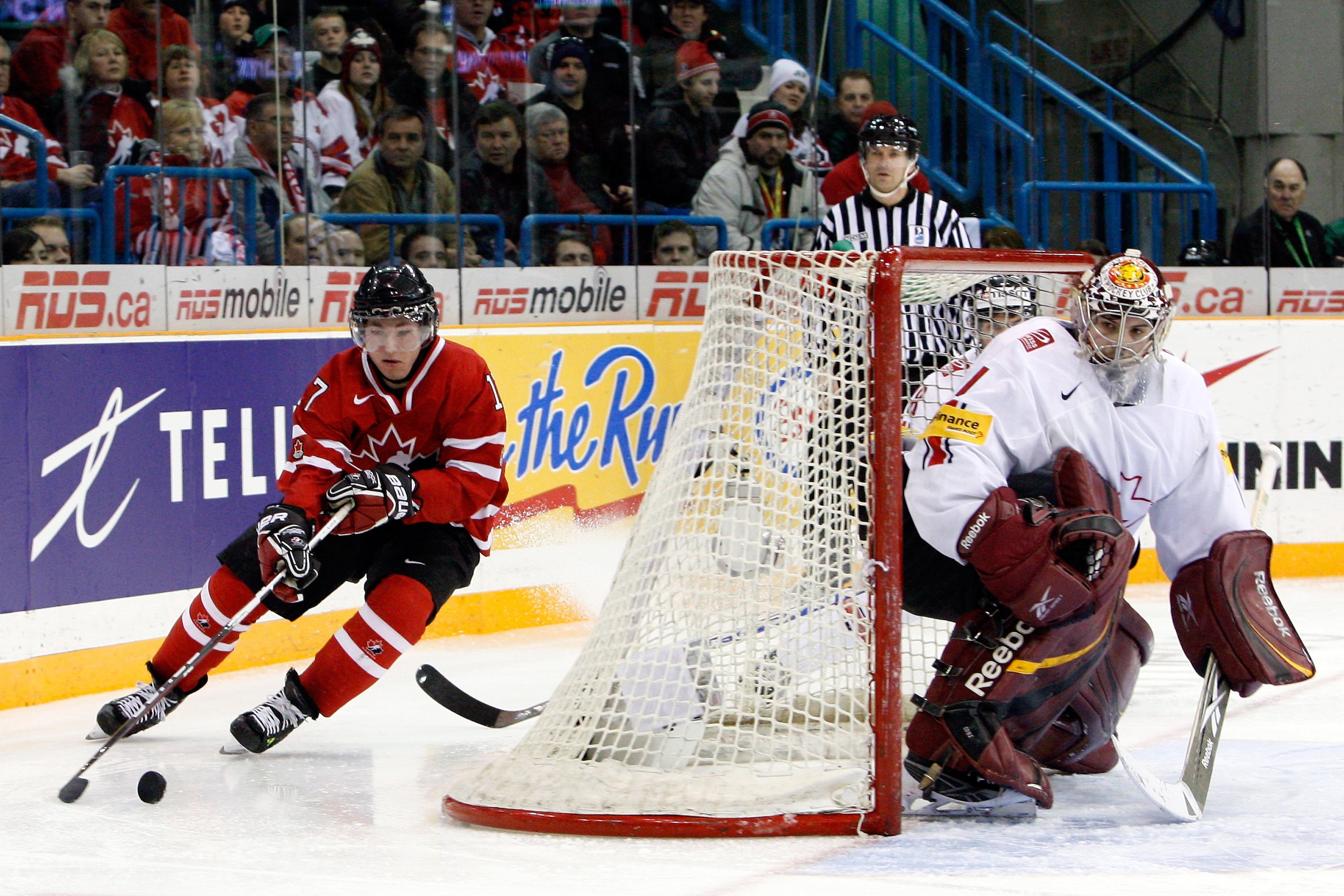 SASKATOON, SK - JANUARY 3:  Brandon Kozun #17 of Team Canada skates with the puck behind the net of Benjamin Conz #1 of Team Switzerland during the 2010 IIHF World Junior Championship Tournament Semifinal game on January 3, 2010 at the Credit Union Centre